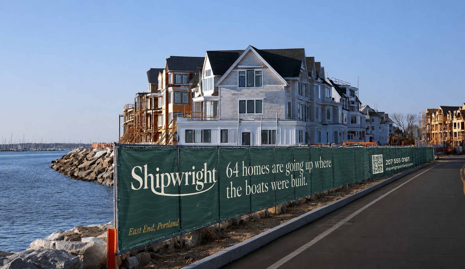Two workers hanging a printed building rendering on a construction fence at sunrise