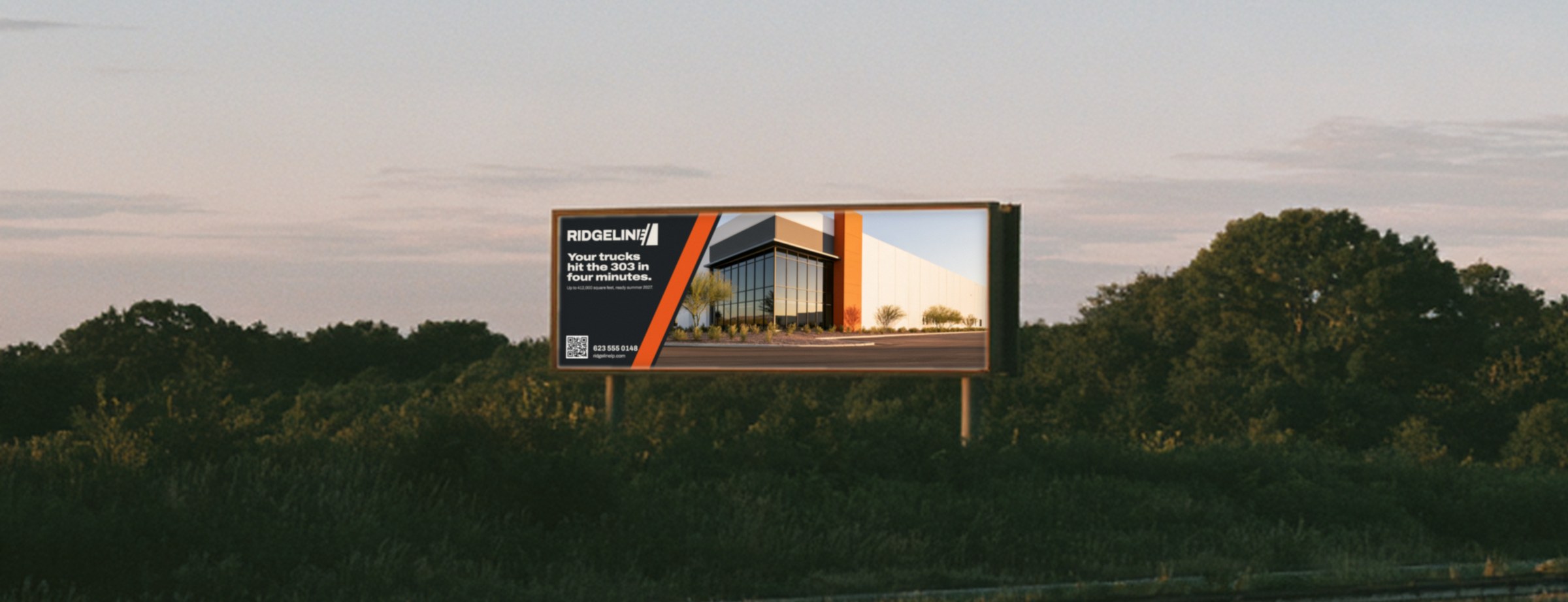 Ridgeline billboard beside an interstate at dusk