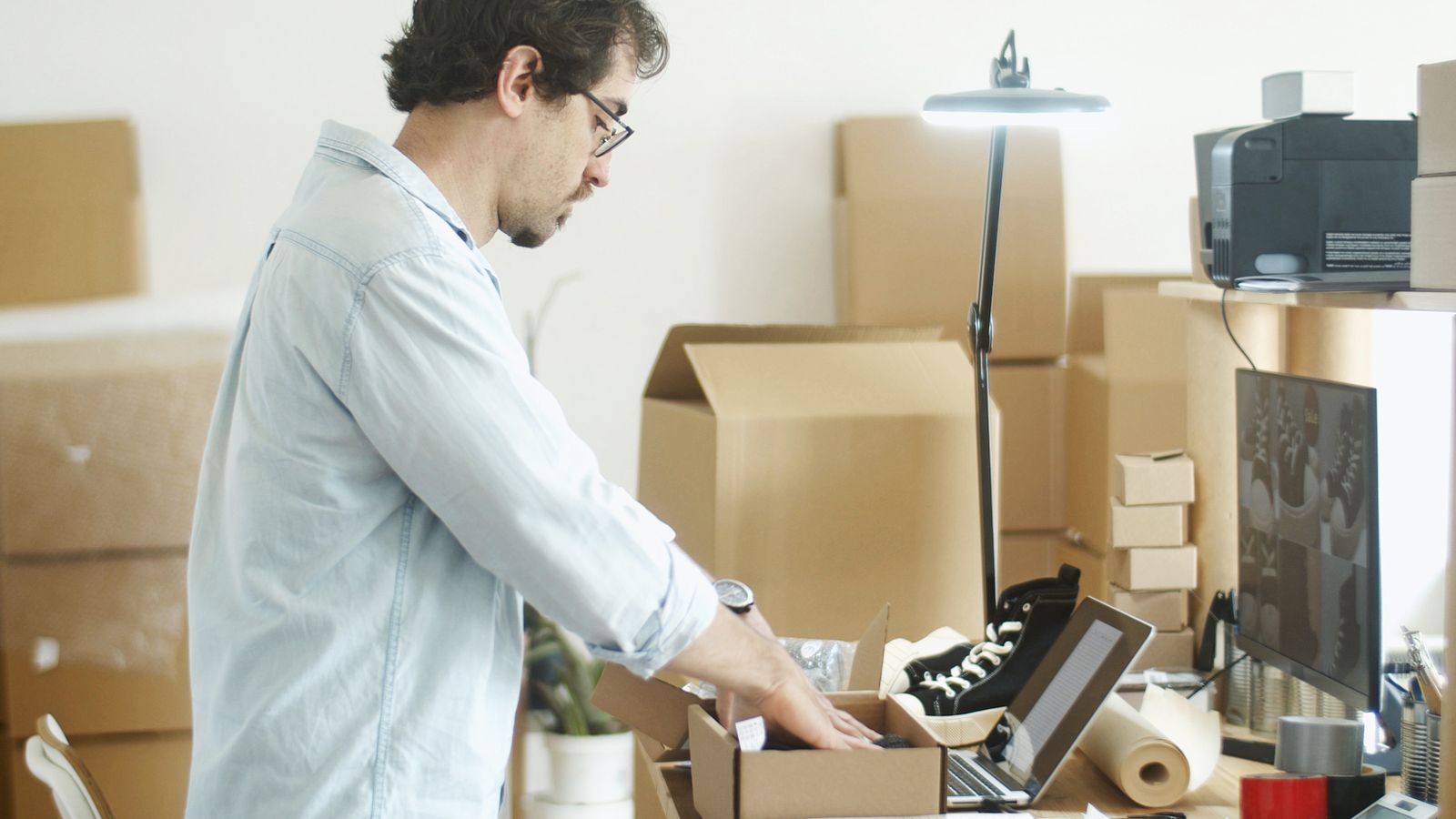 Entrepreneur e-commerce préparant une commande au milieu de cartons, illustrant la réalité du dropshipping en 2026