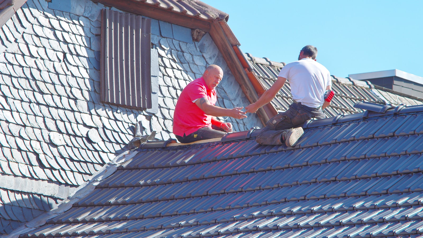 Deux couvreurs travaillant sur un toit en ardoise