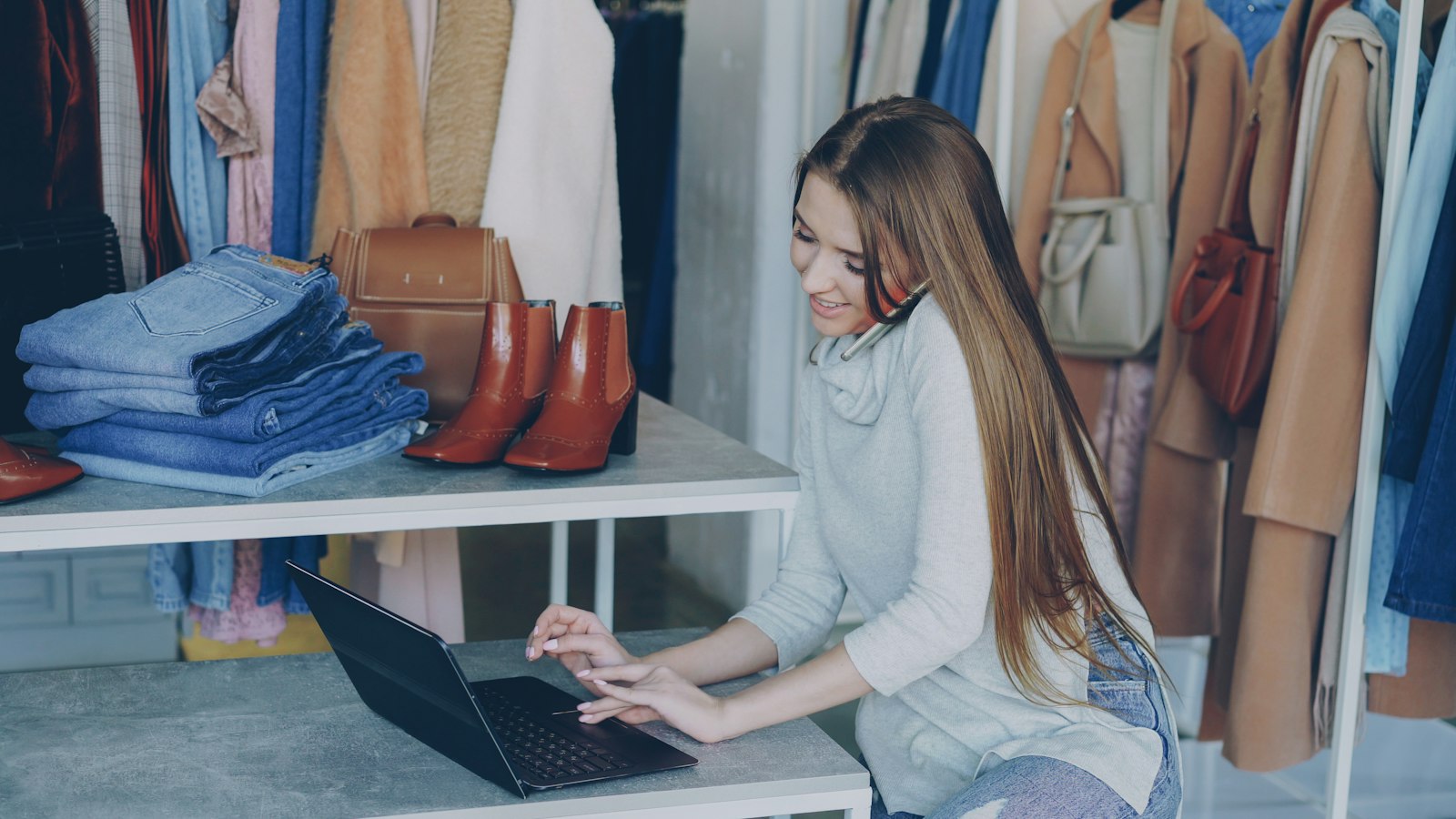 Commerçante qui travaille sur son ordinateur portable dans sa boutique de vêtements, pour créer sa boutique Shopify