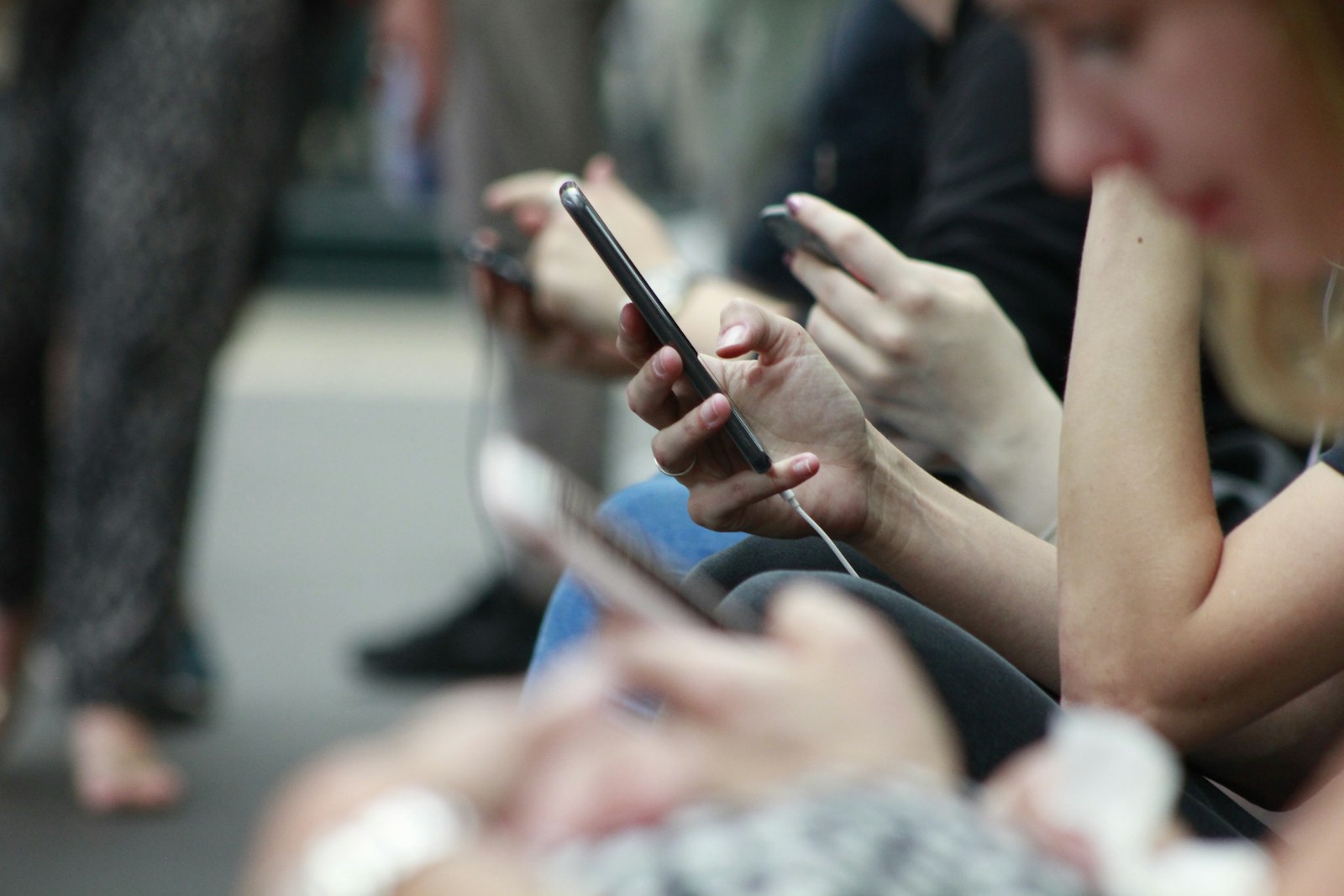 Personnes qui font défiler leur fil d'actualité sur smartphone, là où apparaissent les pubs de la bibliothèque publicitaire Meta