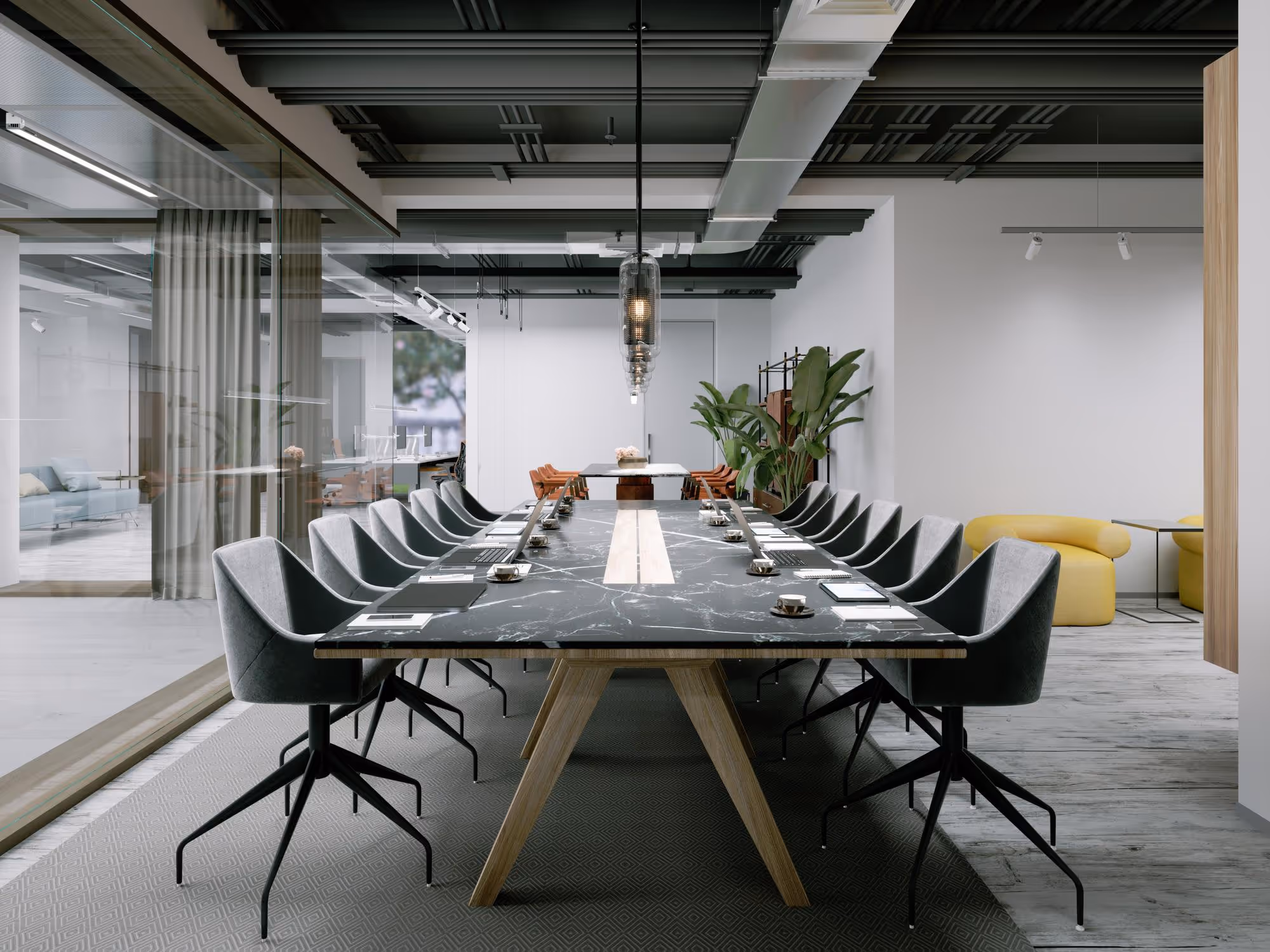 Salle de conférence moderne avec une longue table en marbre noir et des chaises grises, équipée d’ordinateurs portables et de tasses à café.