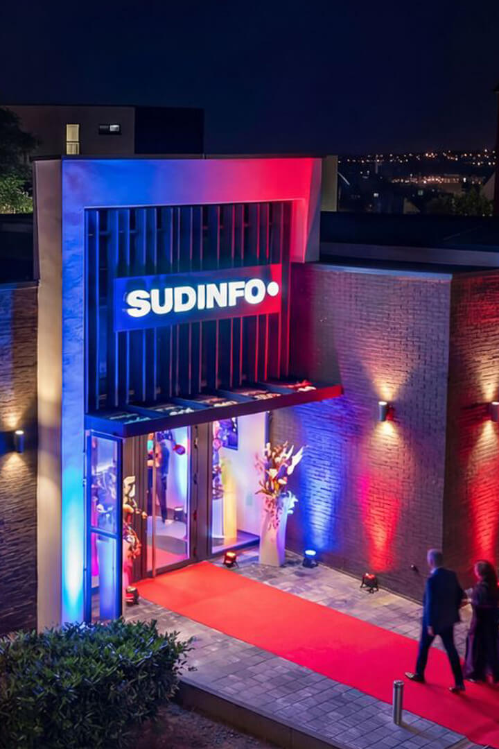 Bâtiment Sudinfo éclairé de nuit avec tapis rouge pour un événement