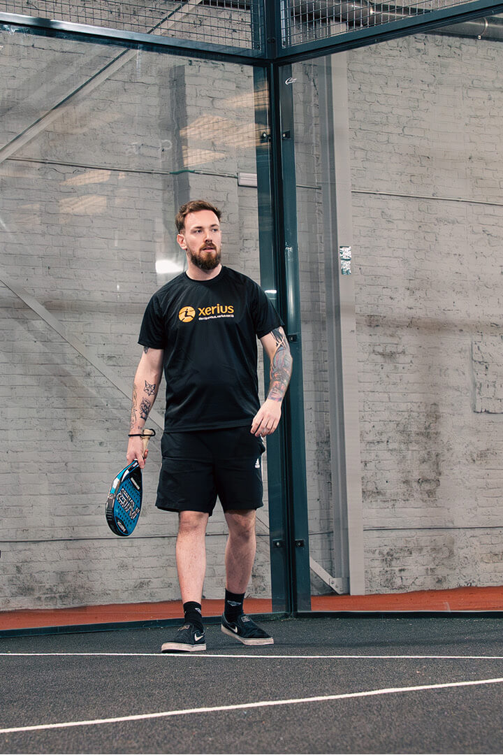 Joueur de padel entrant sur un terrain intérieur avec raquette à la main