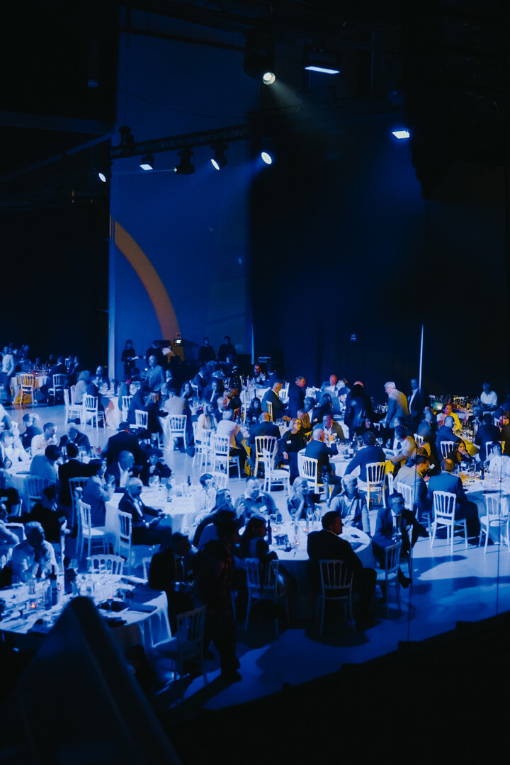 Vue en coulisses d’une salle événementielle avec invités attablés