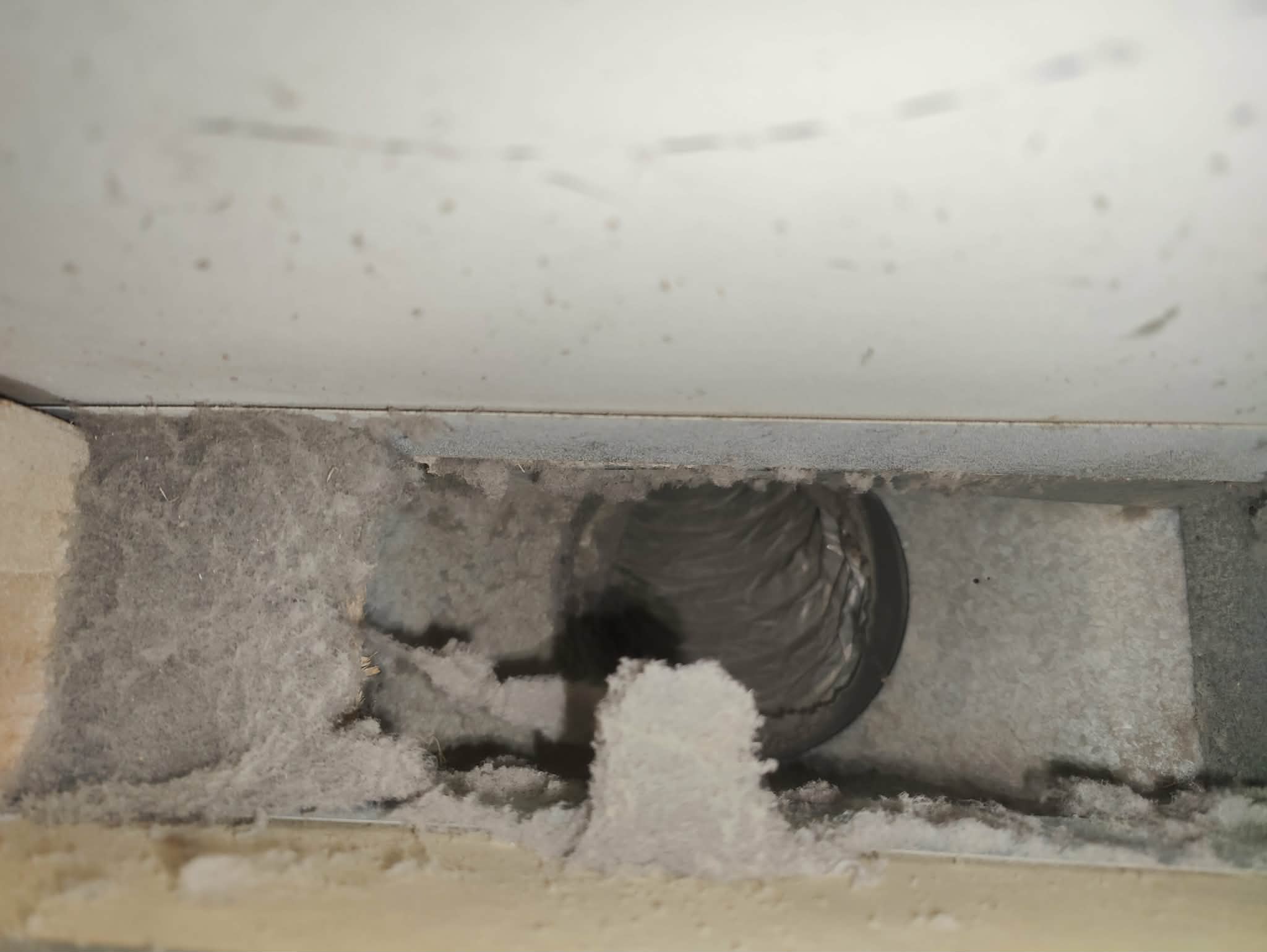 Close-up of a dusty and lint-clogged HVAC duct interior.