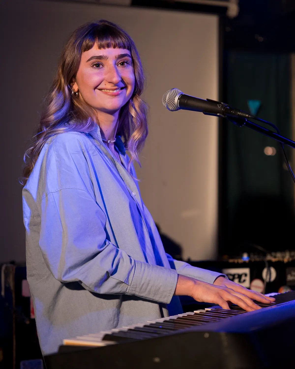 Musicienne souriante au clavier pendant un live, focus sur les artistes musique émergente.