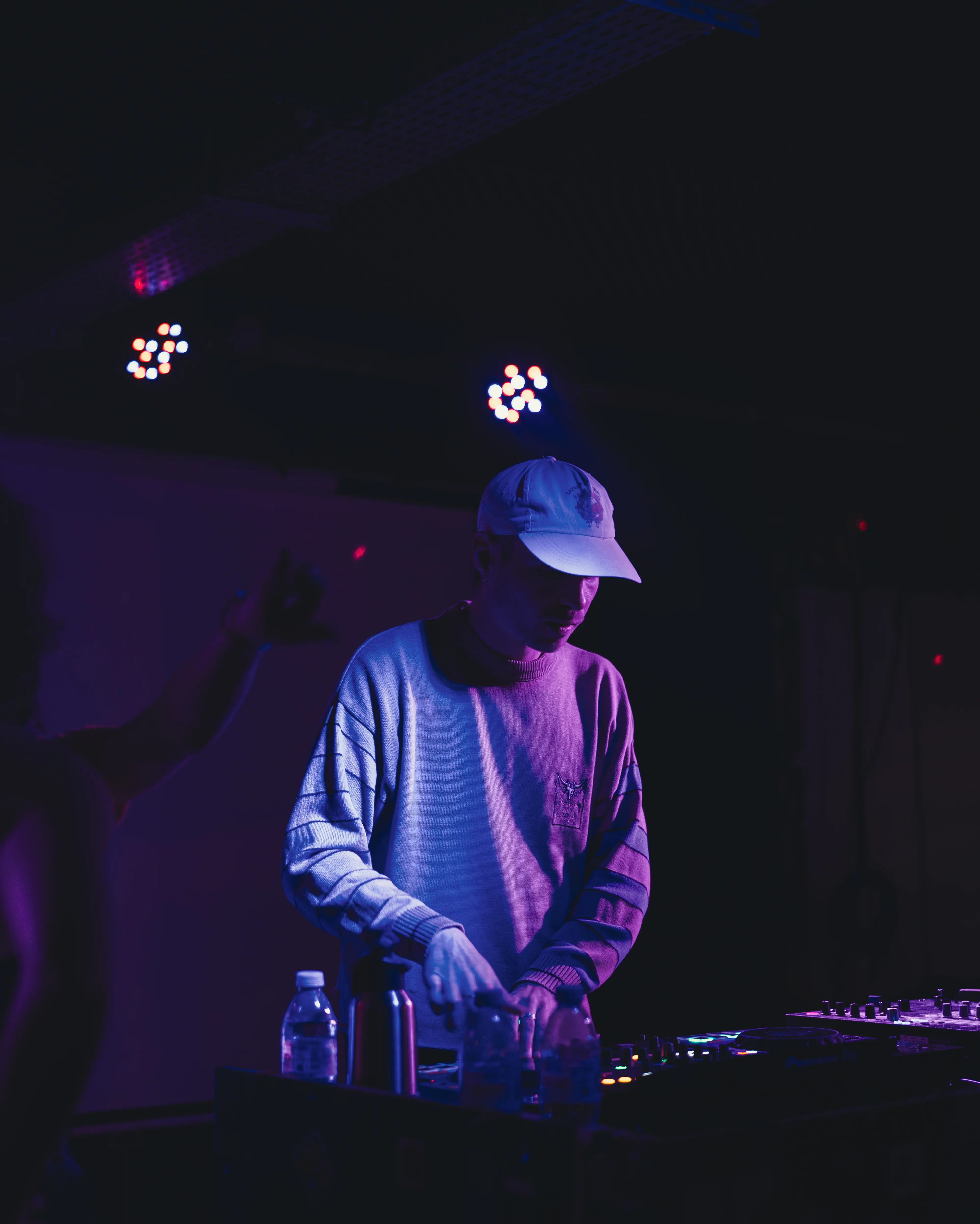 DJ en casquette concentré sur son mix, l'un de nos talents musicaux émergents.