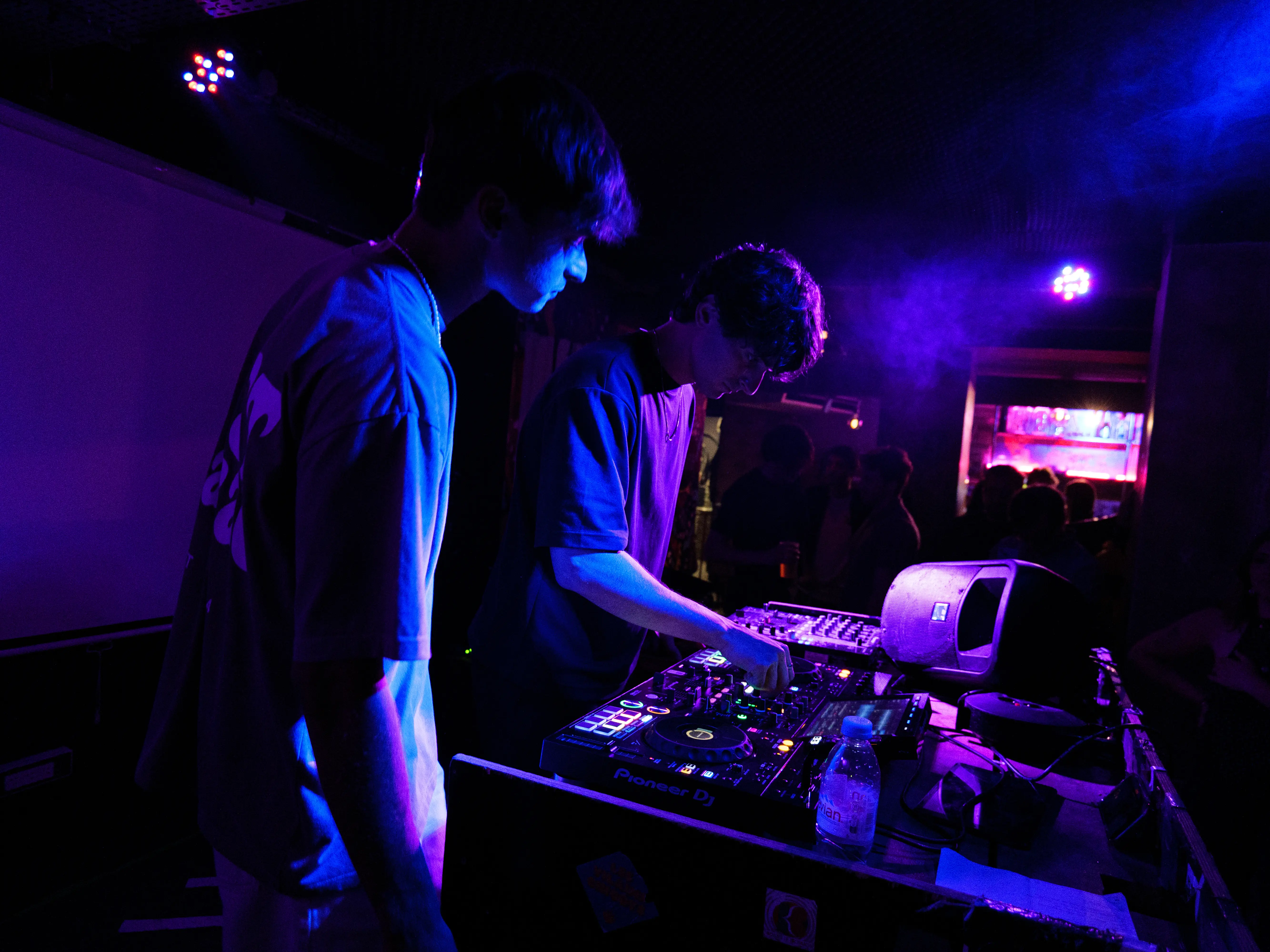 Deux DJs mixant sous des néons violets, mettant en lumière les nouveaux artistes musique.