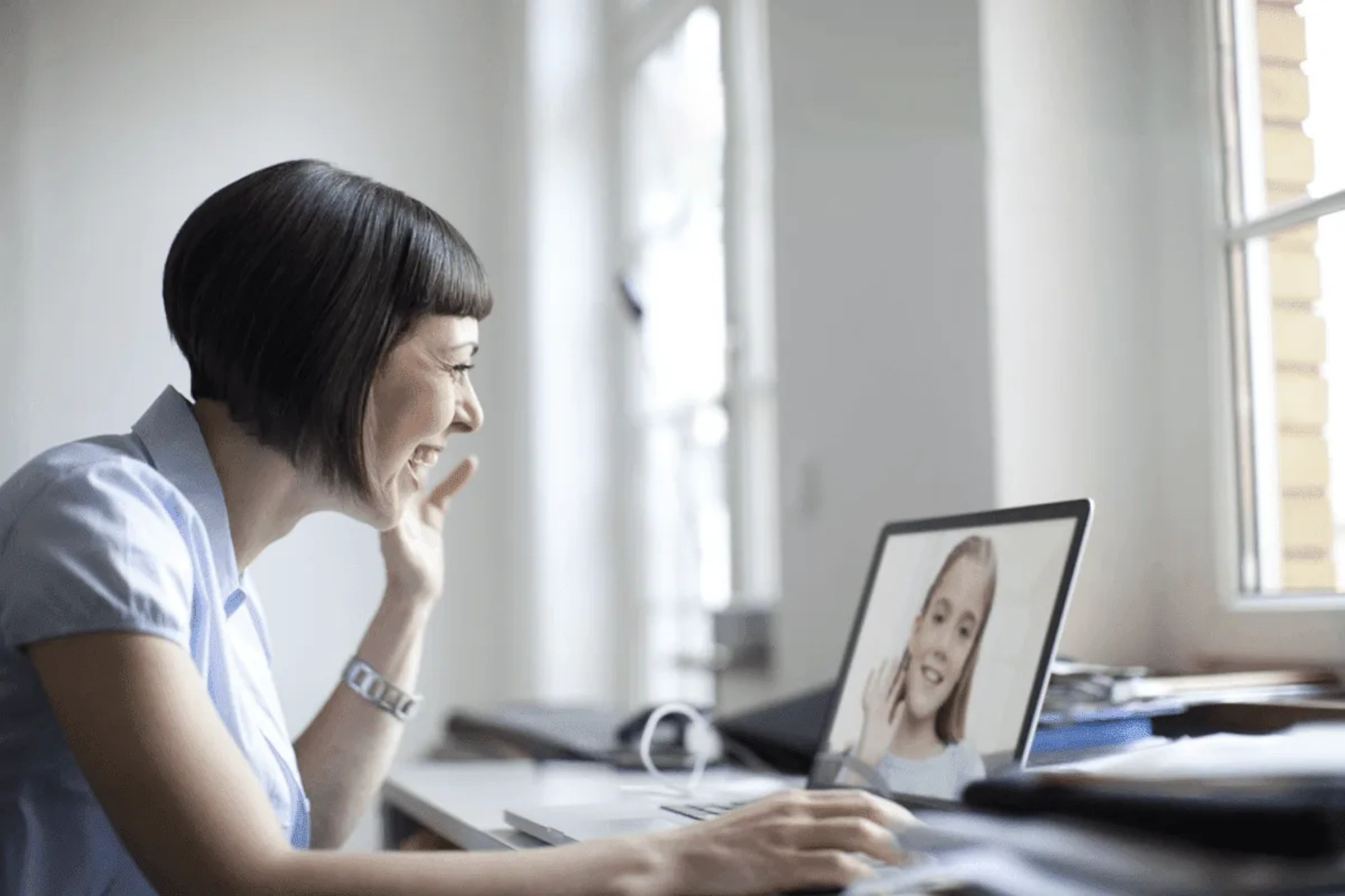 A therapist sitting at her computer talking with a young girl over a video call