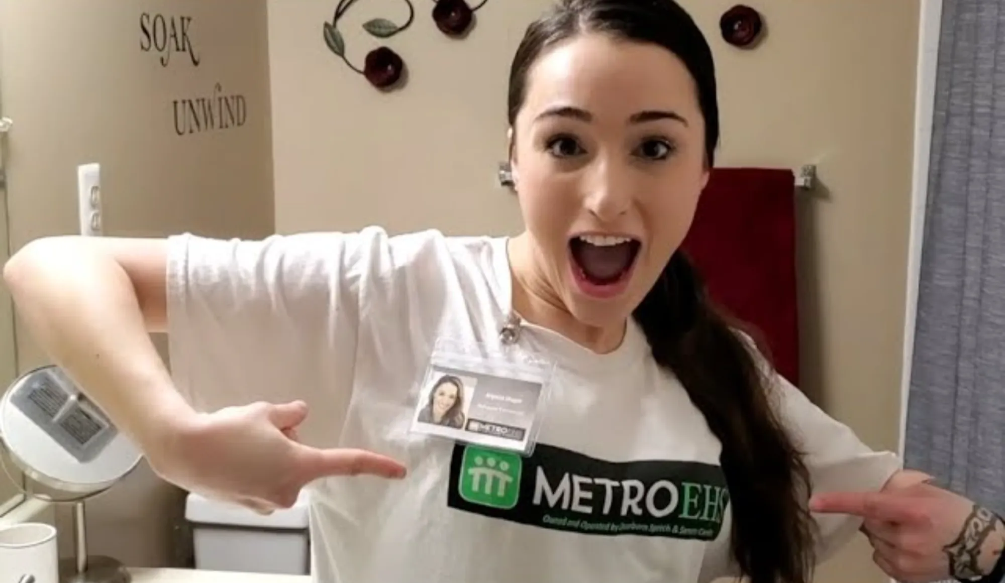 A MetroEHS behavior technician making a funny face and pointing to the MetroEHS logo on her shirt
