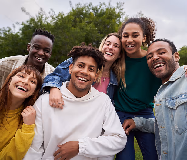 Large diverse group of joyful global youth laughing together outdoors, promoting mental health and belonging