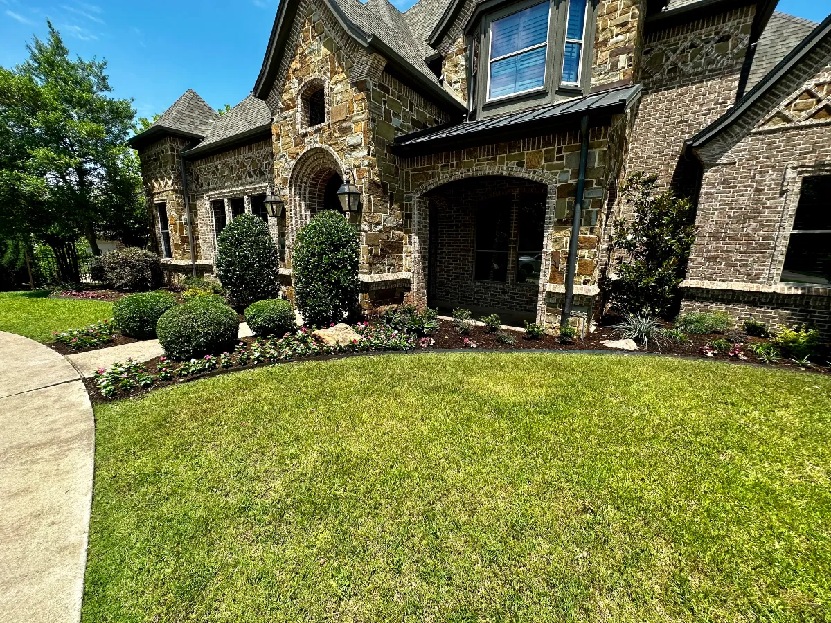 Manicured front lawn and landscaped flower beds surrounding a stone home