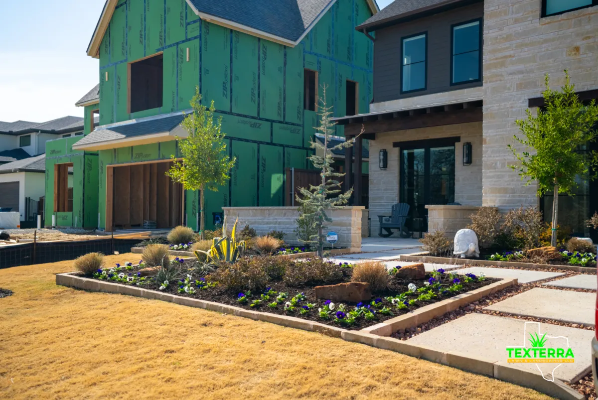 New residential landscape installation with young trees, shrubs, and flower beds