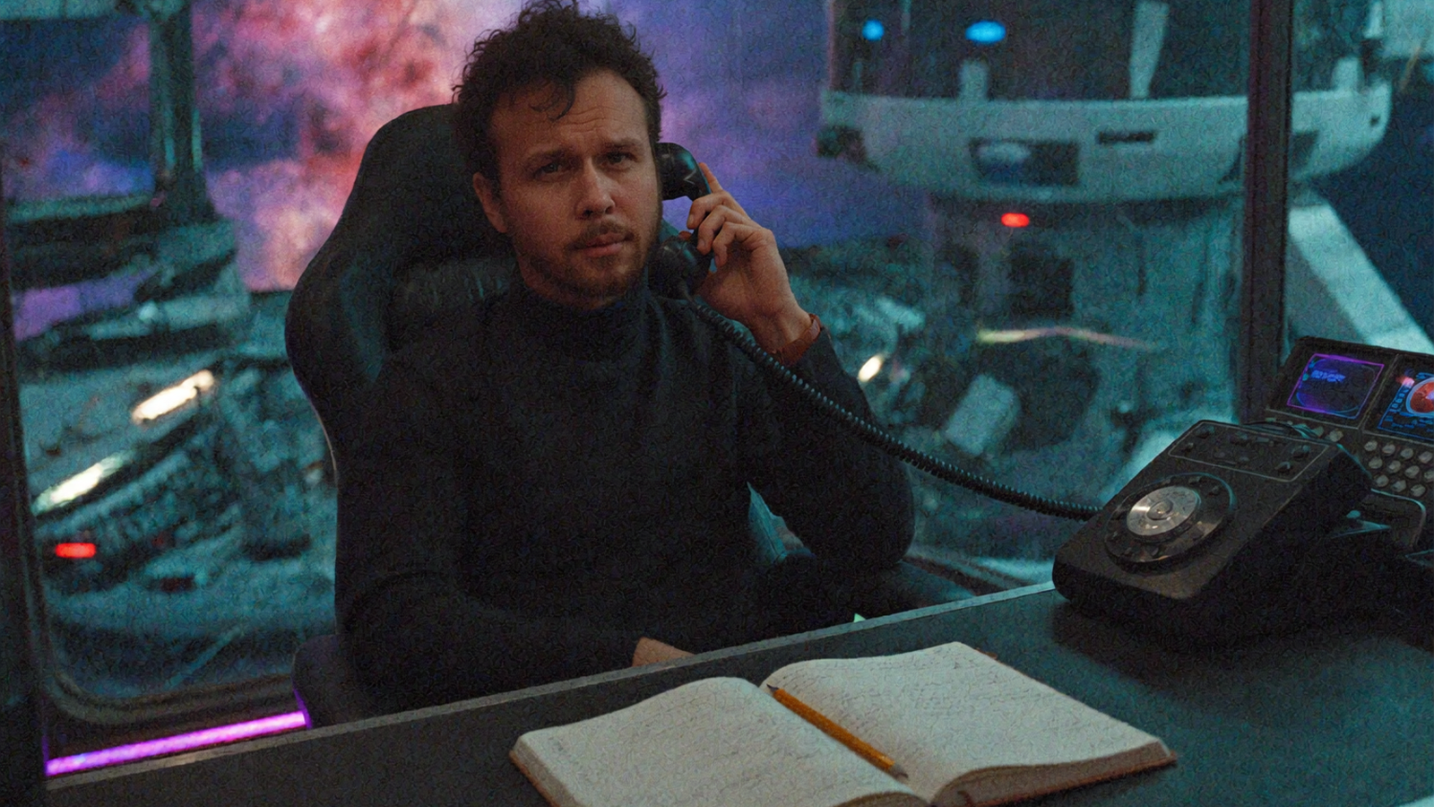 A man in a dark turtleneck takes a call on a vintage handset at his desk in a retro-futuristic space station, a glowing nebula visible through the window behind him.