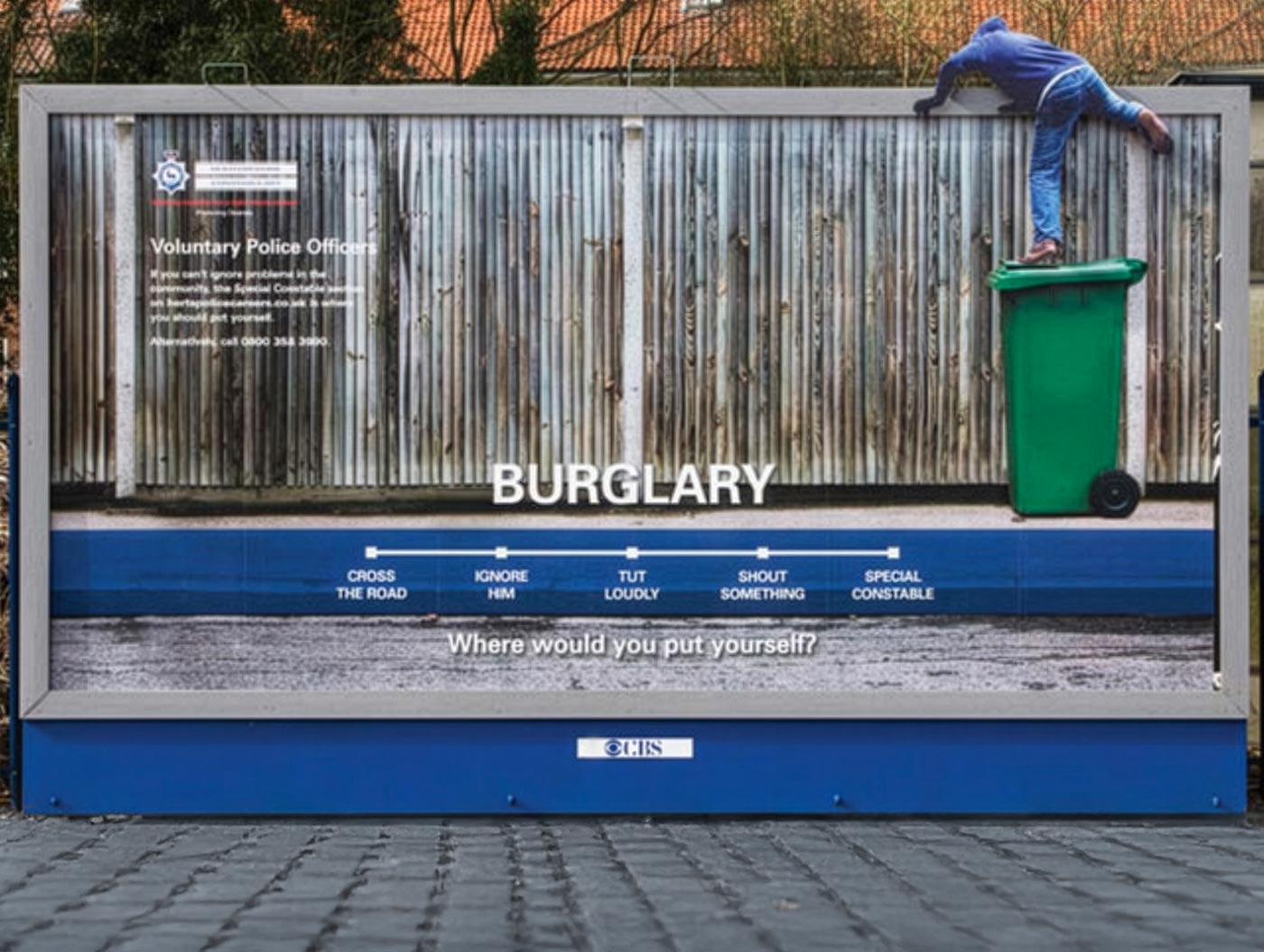 Billboard showing a person climbing a green trash bin to scale a corrugated metal fence, with text about burglary and a scale of responses to a crime.