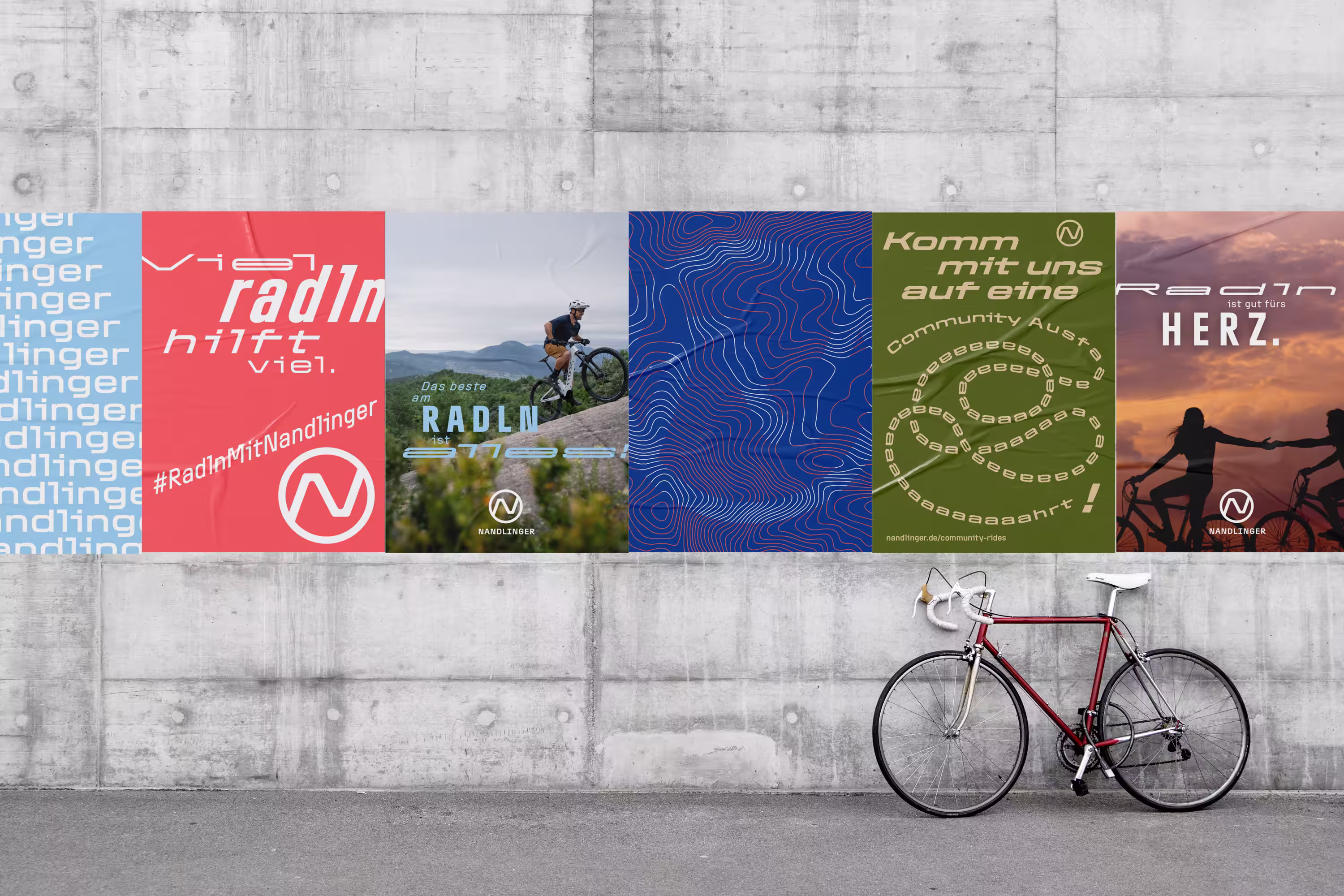 Nandlinger: mehrere Plakate an einer Betonwand, davor ein Fahrrad