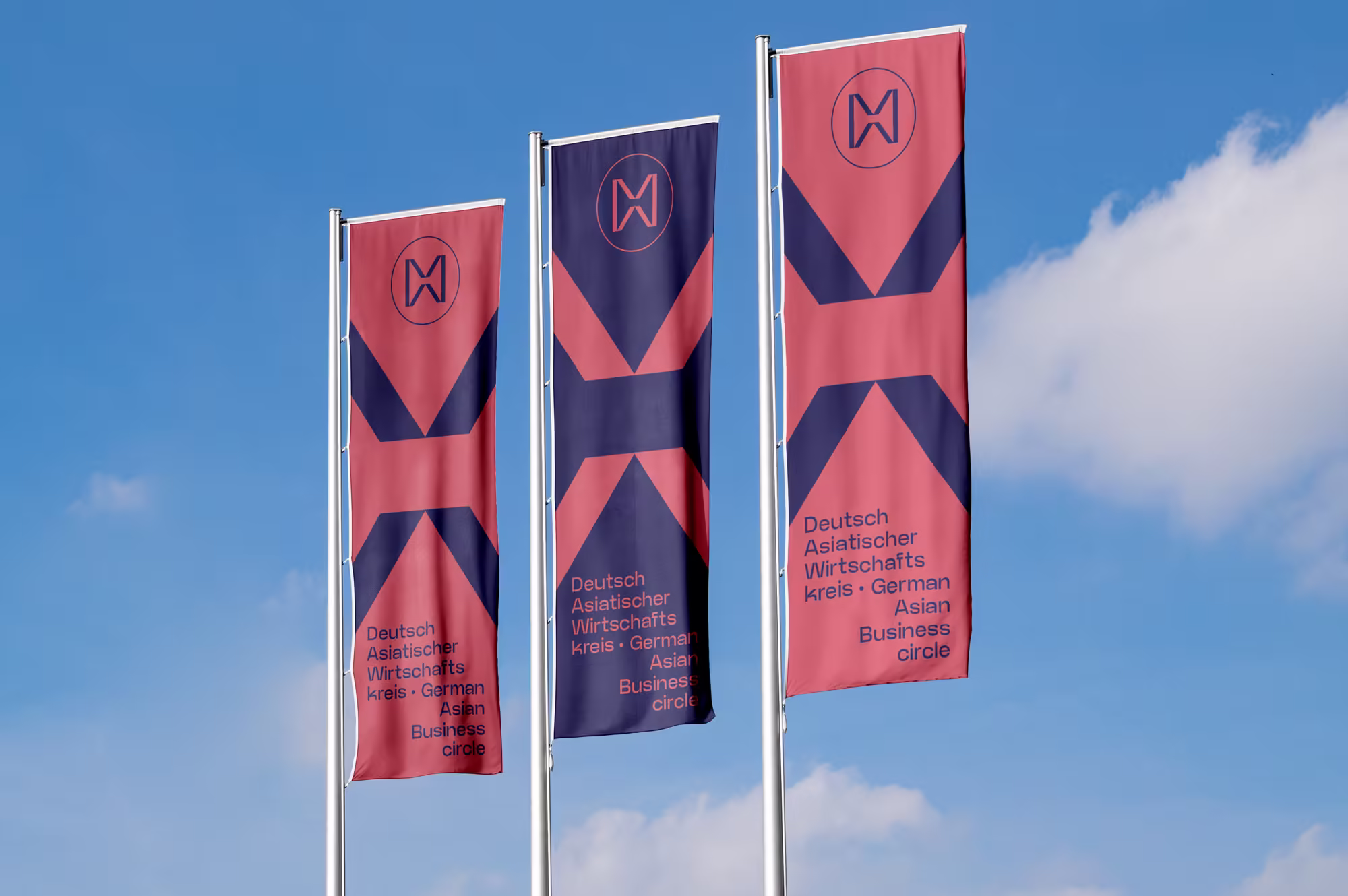 Deutsch Asiatischer Wirtschaftskreis: drei Fahnen mit Logo in Blau und Rot vor Himmel