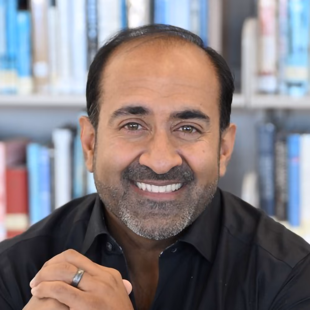 Porträt von Rohit, lächelnder Mann mit Bart vor Bücherregal