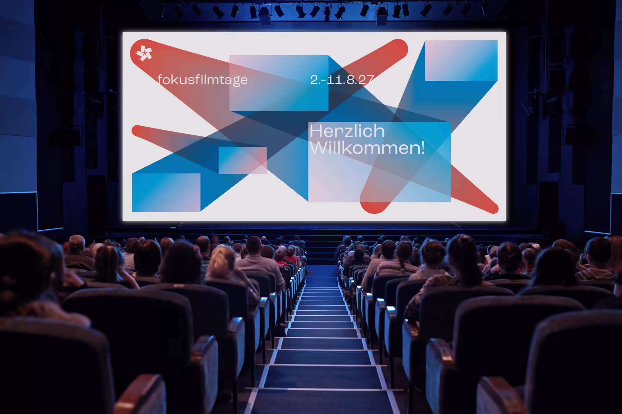 focusfilmfestival: Kinoleinwand mit blau-rotem Muster vor Publikum