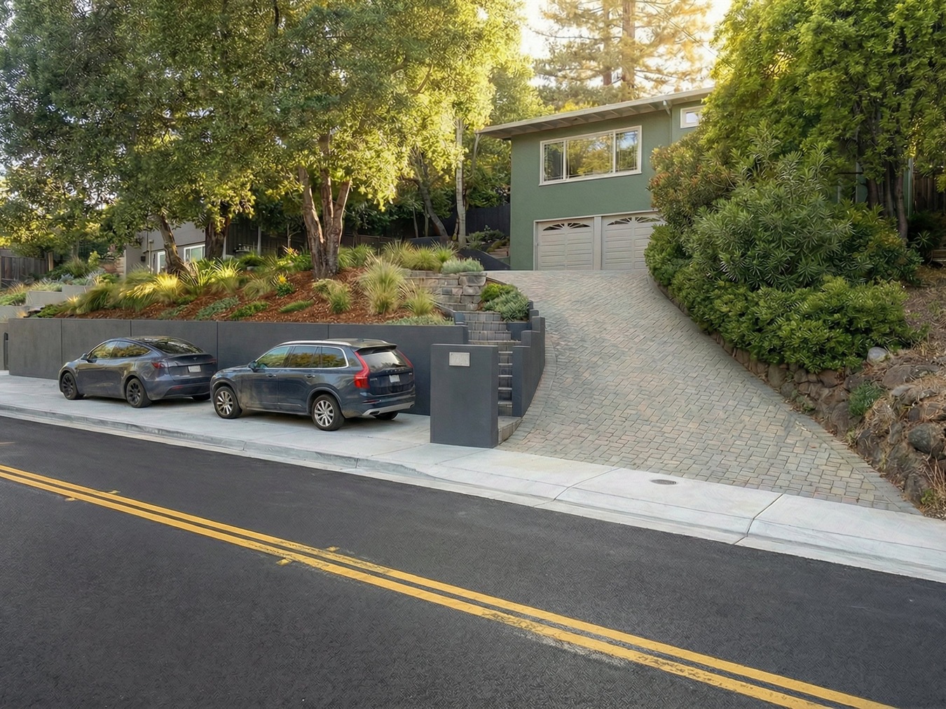Street view showing the new retaining wall with parking pads and mail drop at the steep driveway.