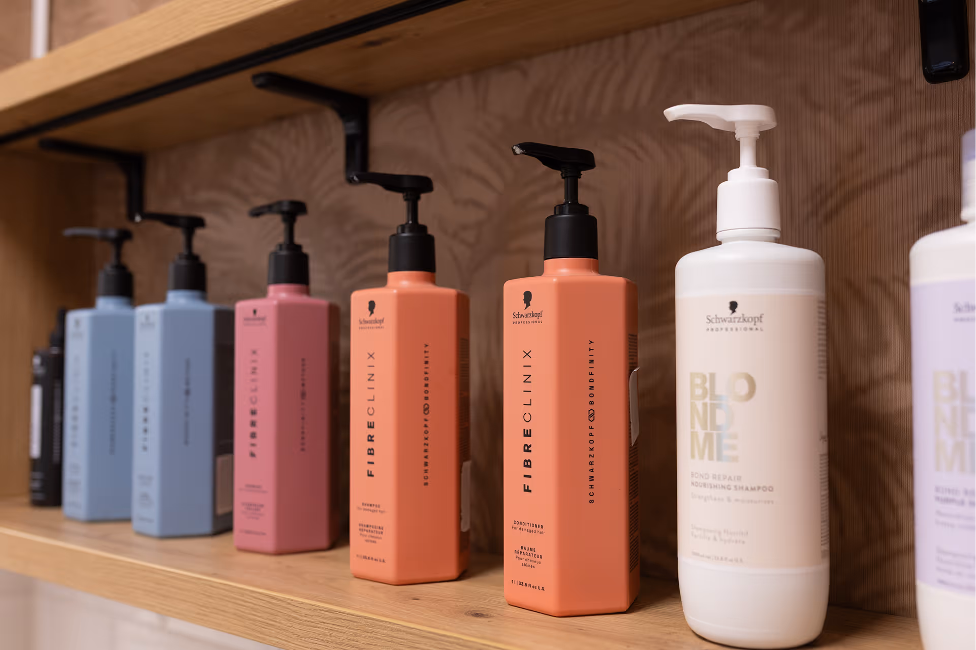 Polc különféle Schwarzkopf Professional hajápolási termékekkel, köztük Fibreclinix kondicionálókkal és BlondMe samponnal.