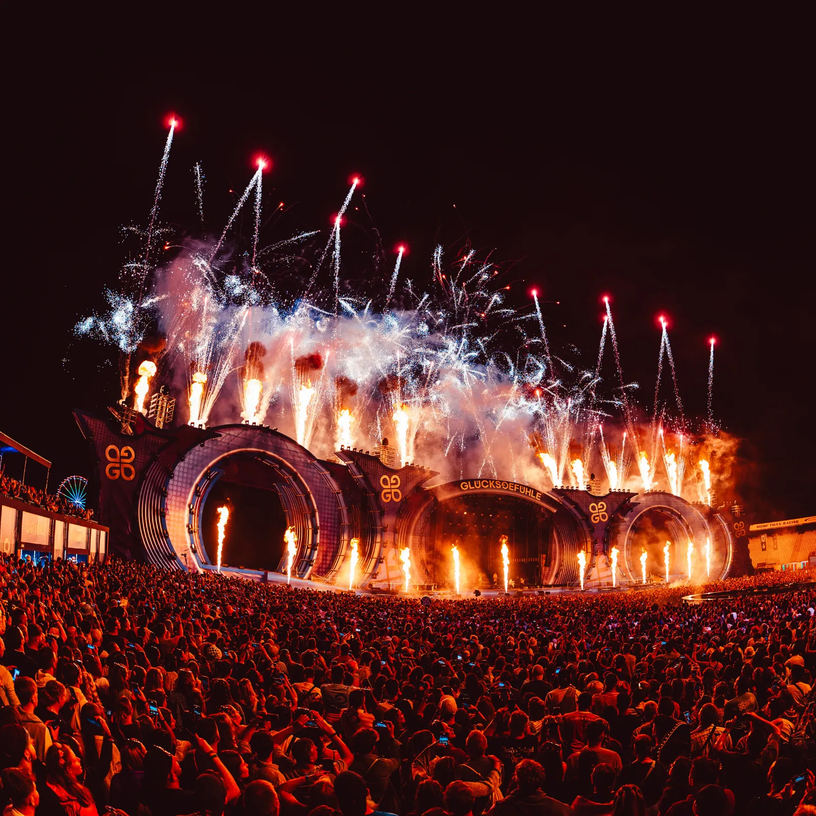 Festivalbühne mit Pyrotechnik vor dichtem Publikum