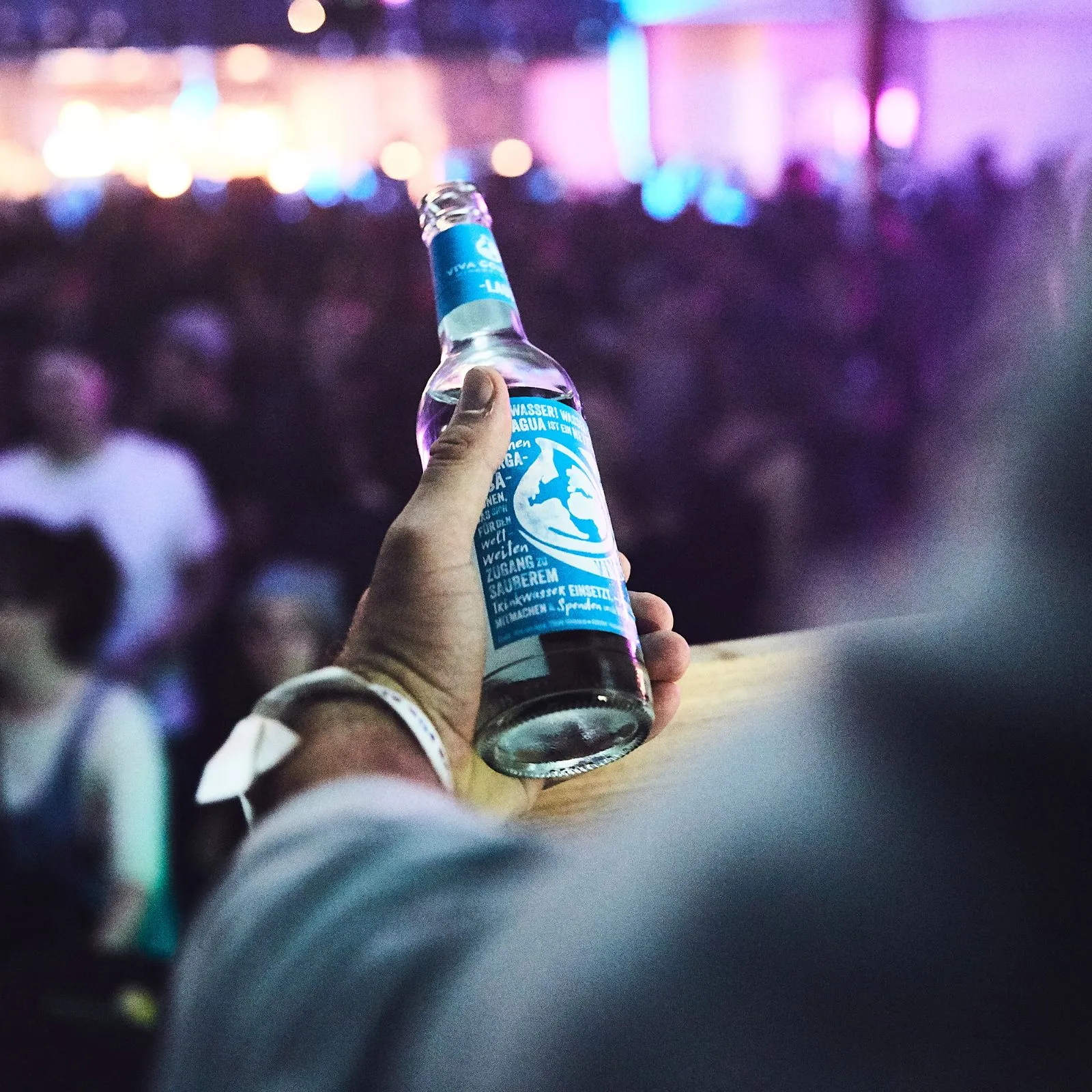 Getränkeflasche in einer Hand vor der Festivalbühne