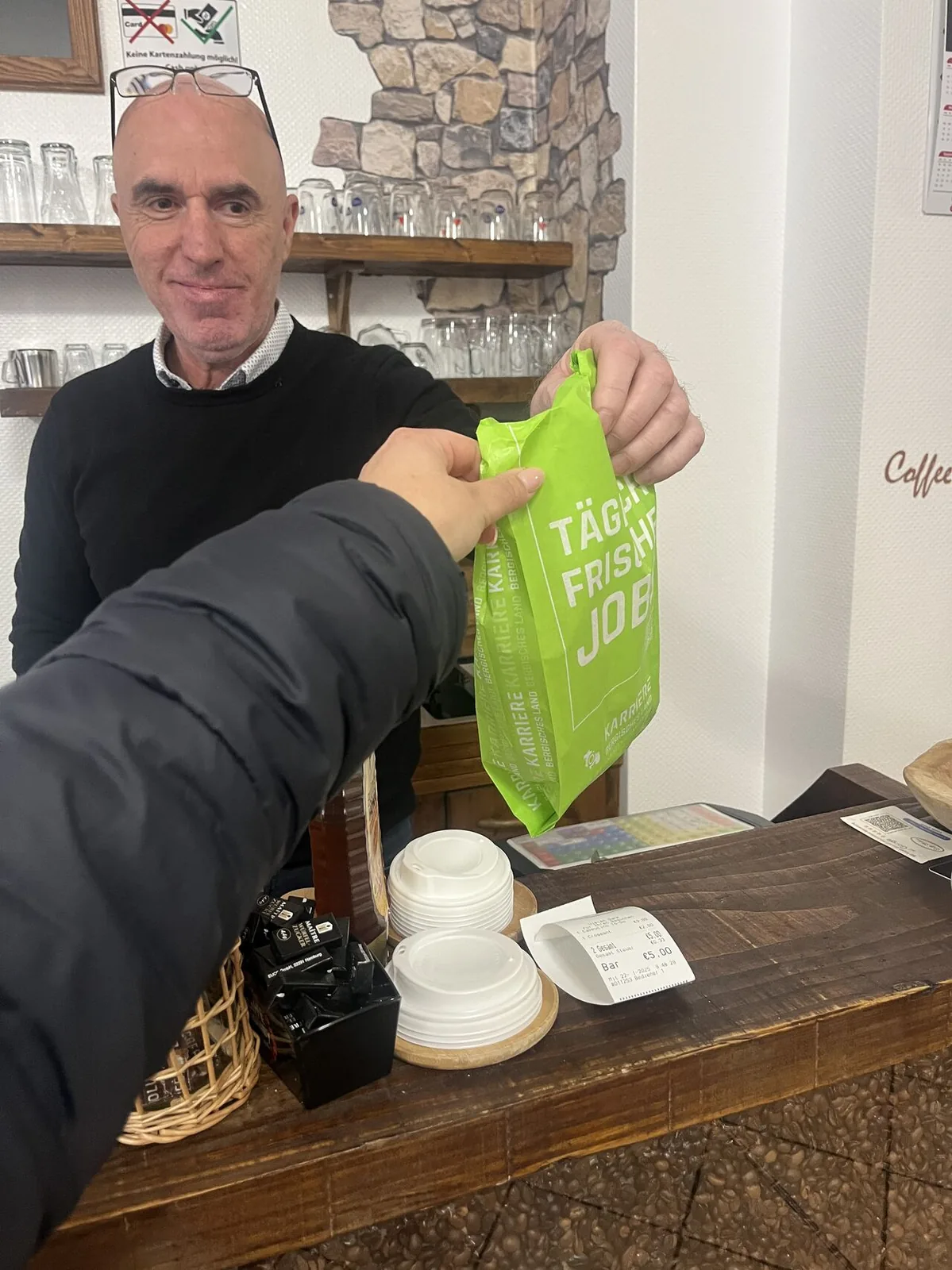 Kunde erhält im Café eine bedruckte Brötchentüte mit Jobportal-Werbung