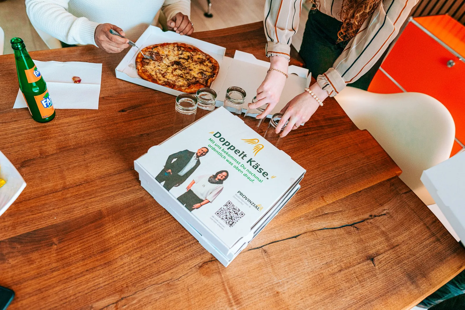 Pizza und bedruckte Provinzial-Pizzakartons auf einem Wohnzimmertisch