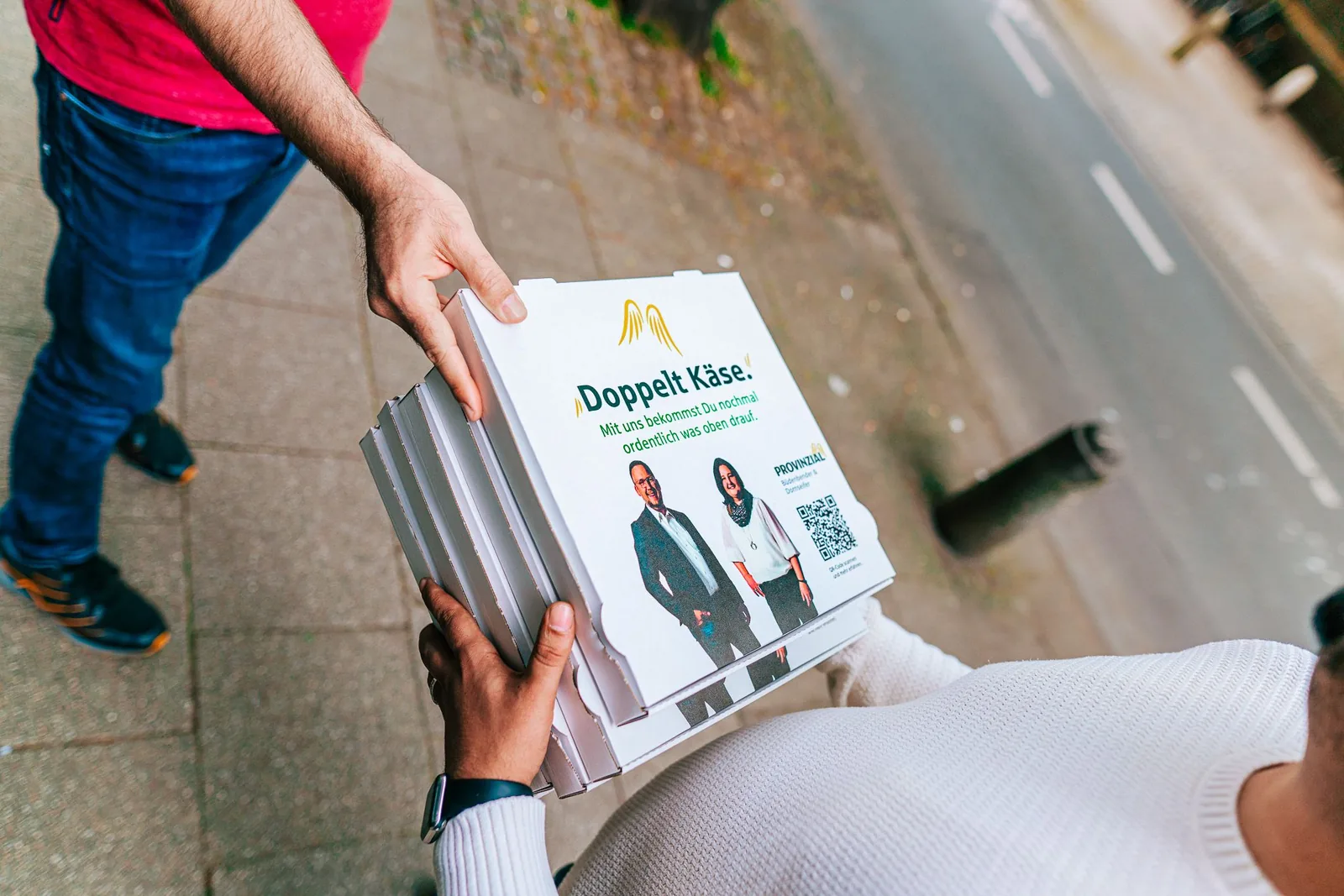 Promoter übergibt auf der Straße einen bedruckten Provinzial-Pizzakarton