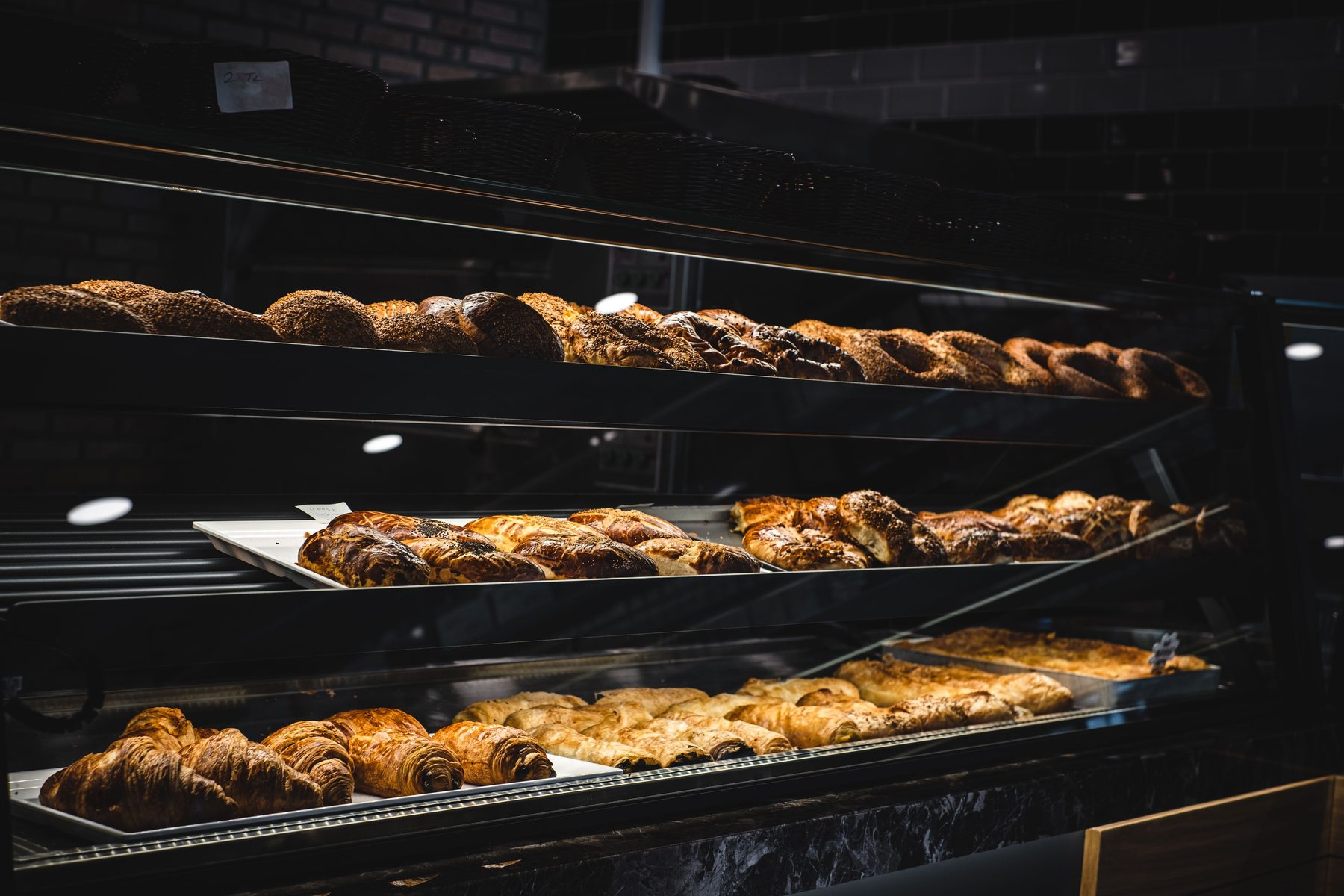 Beleuchtete Auslage einer Bäckerei mit Croissants, Brot und Gebäck
