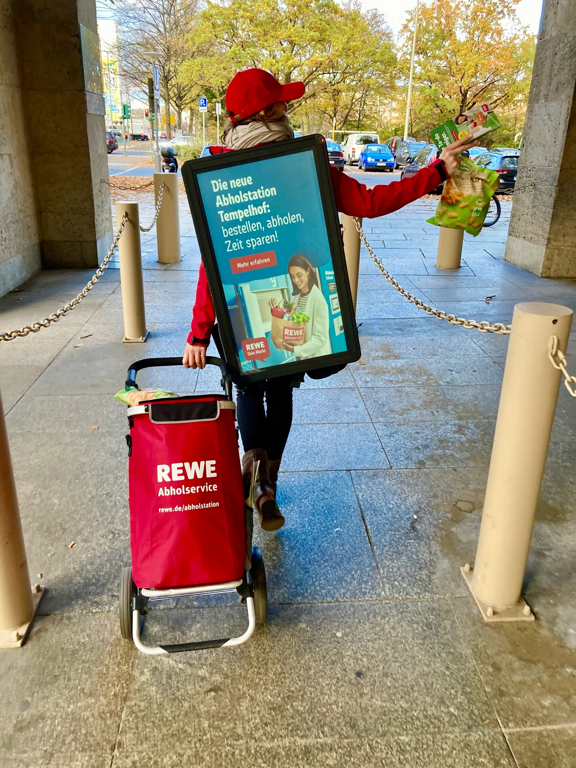 Promoter mit Walking Screen übergibt einer Passantin einen Flyer