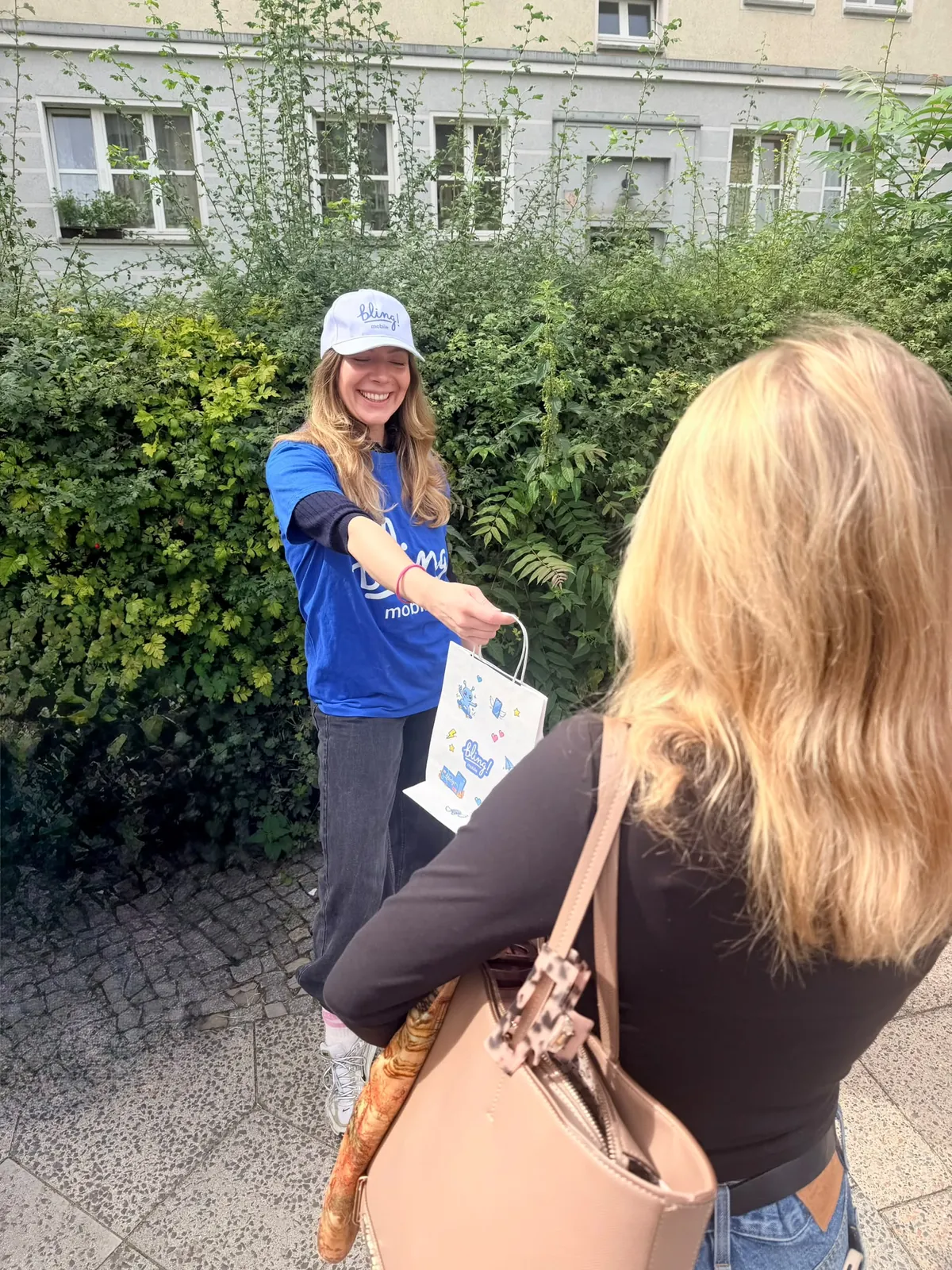 Promoterin von Touchpoint Media im Gespräch mit einer Passantin, übergibt eine Produkttasche