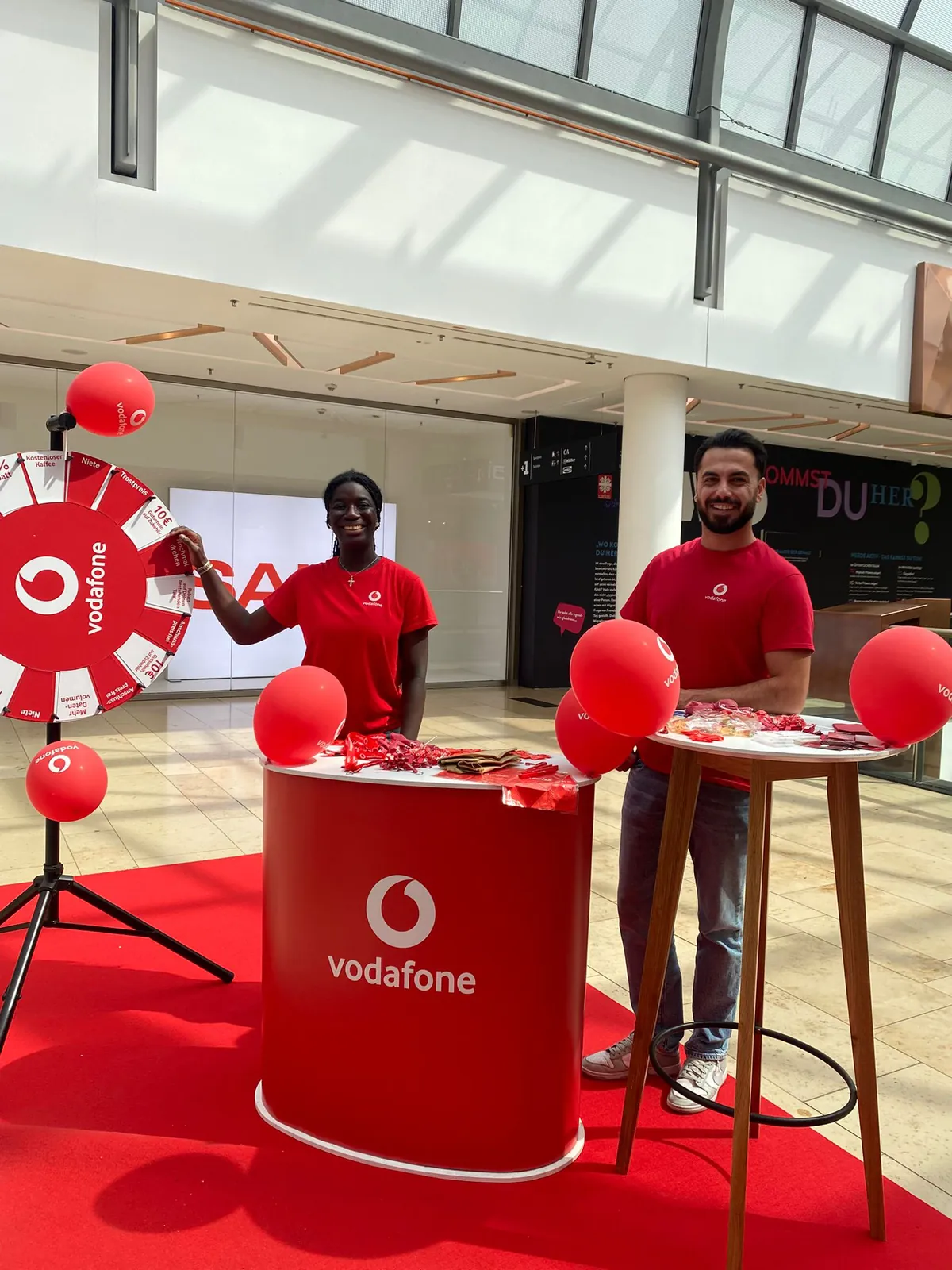 Zwei Promoter an einem Vodafone-Stand mit Glücksrad im Einkaufszentrum