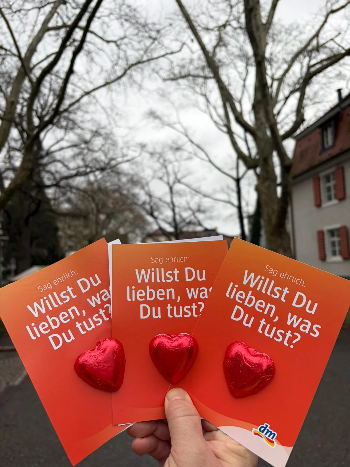 Hand hält Flyer mit Schoko-Herzen aus einer Sampling-Aktion