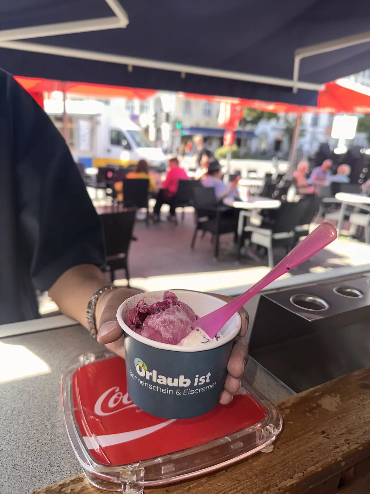 Bedruckter Urlaubsguru-Eisbecher auf einem Tisch vor einer Eisdiele