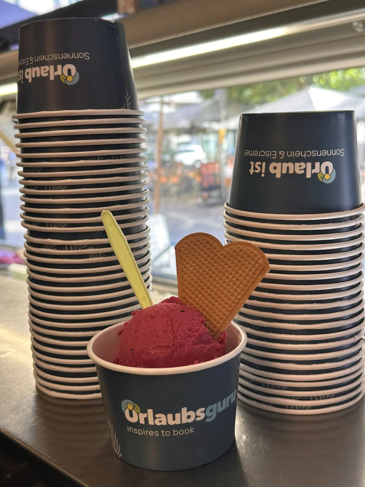 Stapel bedruckter Urlaubsguru-Eisbecher in einer Eisdiele