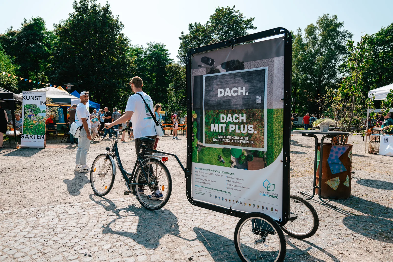 Bike Poster mit Gründach-Motiv in einer belebten Fußgängerzone