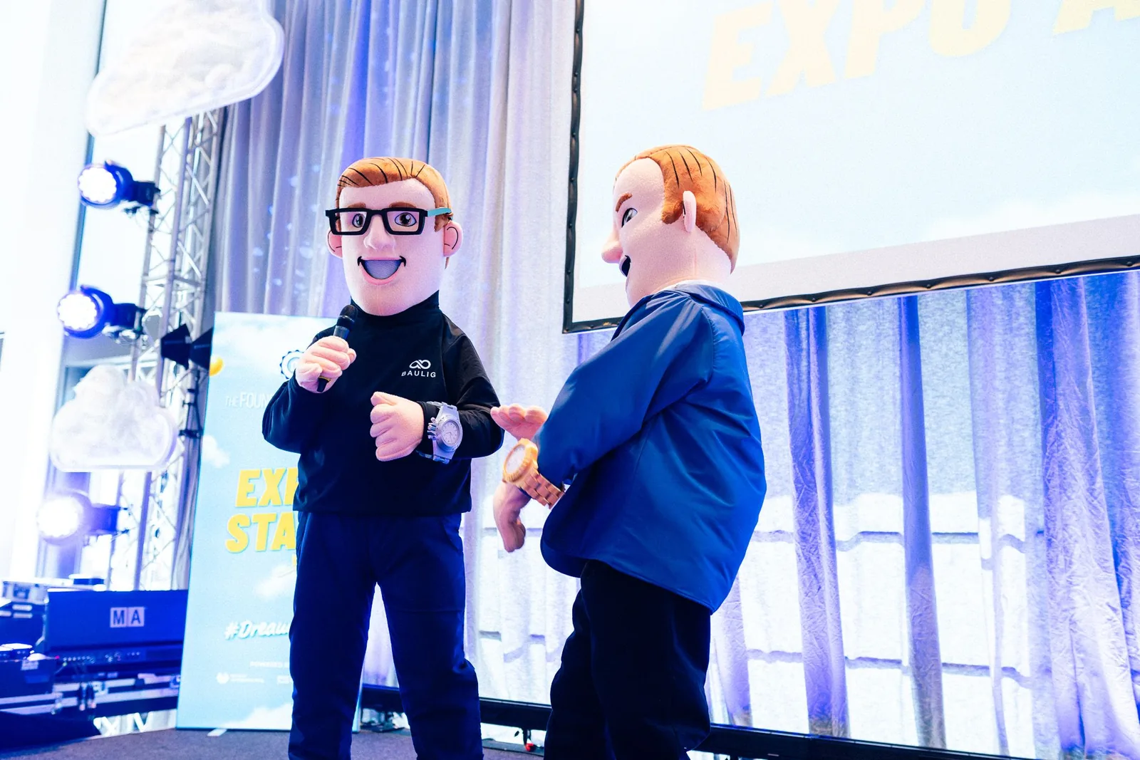 Maskottchen und Moderator bei einer Bühnenaktion vor Publikum