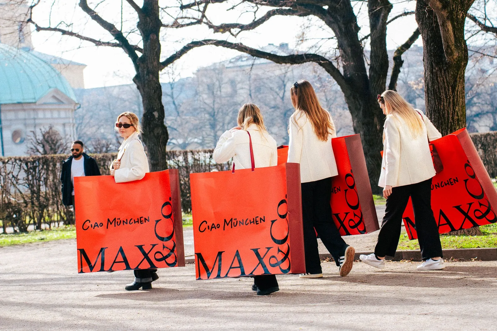 Promoterinnen tragen MAX&Co Aktionstaschen durch einen Park