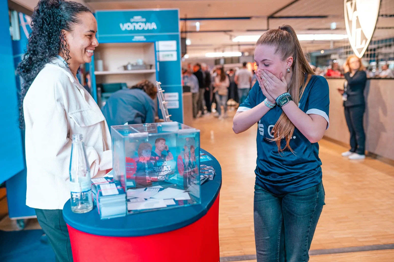 Hostess betreut eine Besucherin am Gewinnspielstand auf der Messe