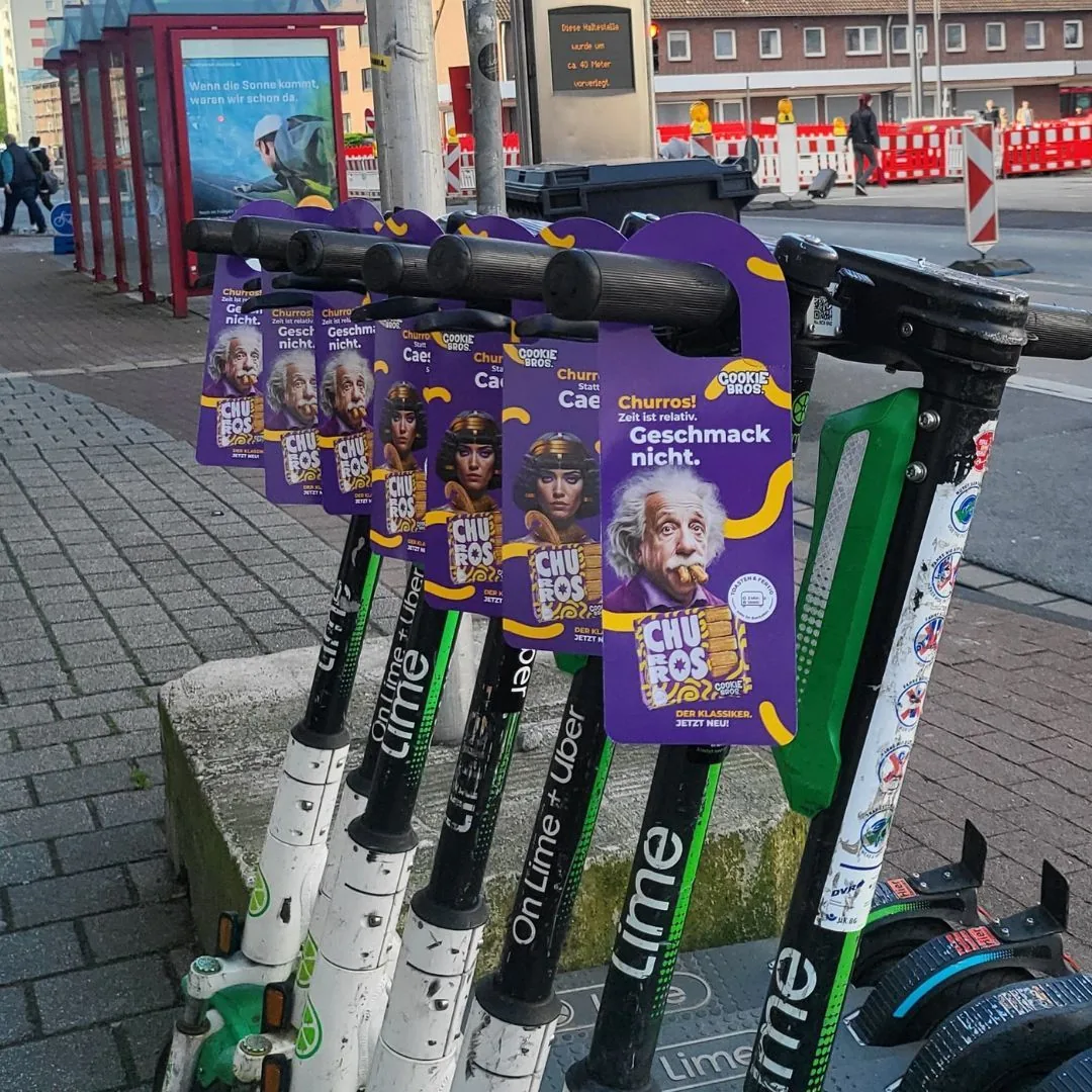 Door Tags mit Werbeaufdruck an geparkten E-Scootern im Stadtgebiet