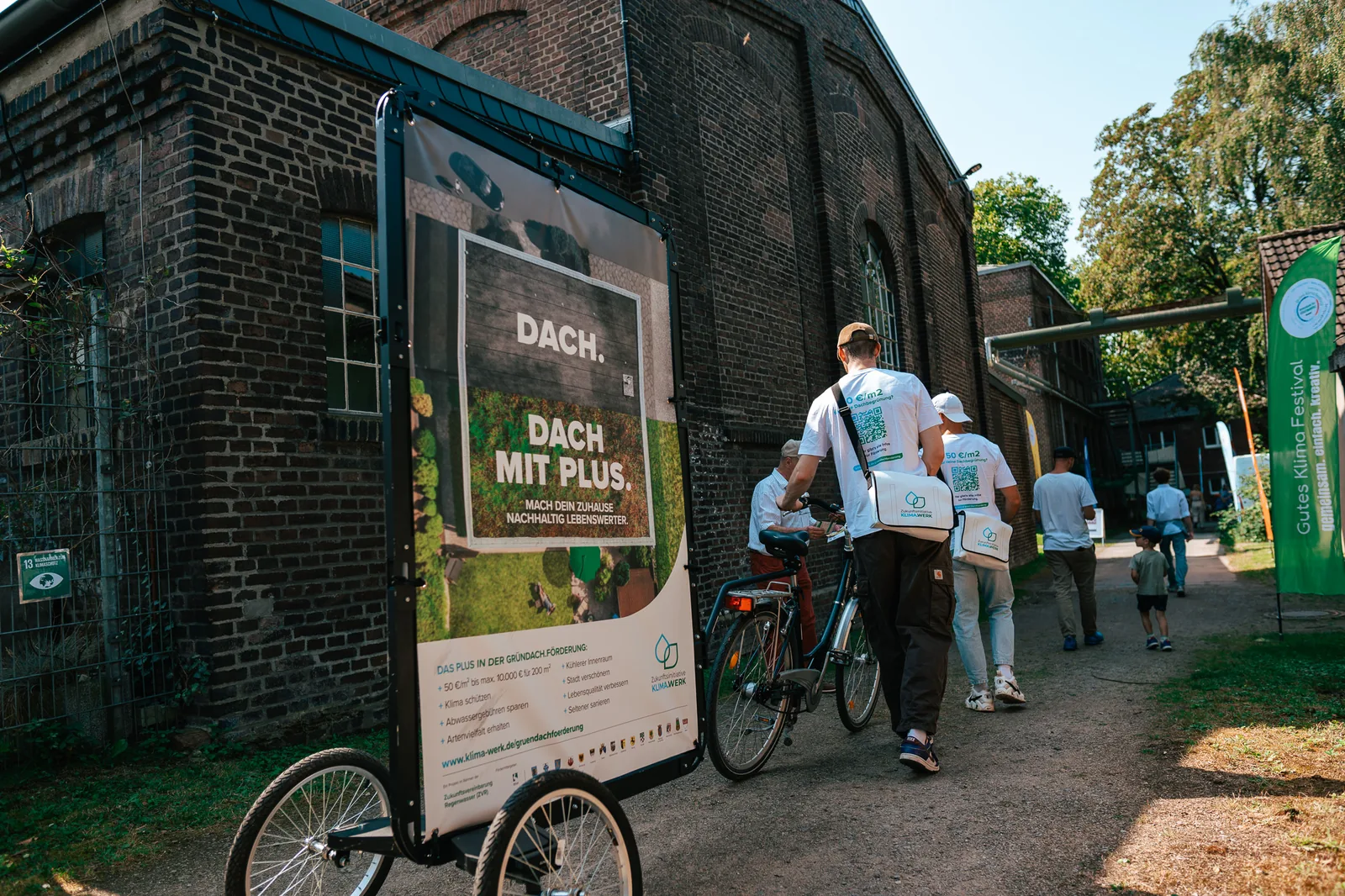 Bike Poster mit Gründach-Motiv vor einer Backsteinfassade