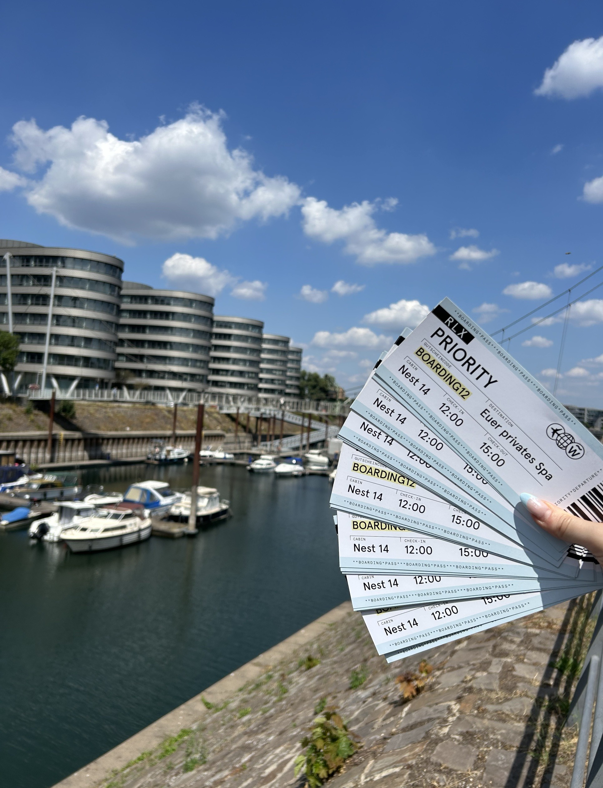 Hand hält mehrere Bordkarten-Flyer auf, im Hintergrund der Duisburger Innenhafen
