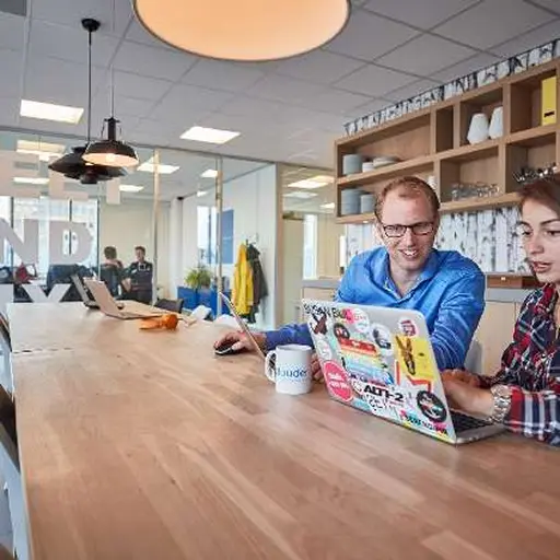 Two people working side-by-side in an office environment