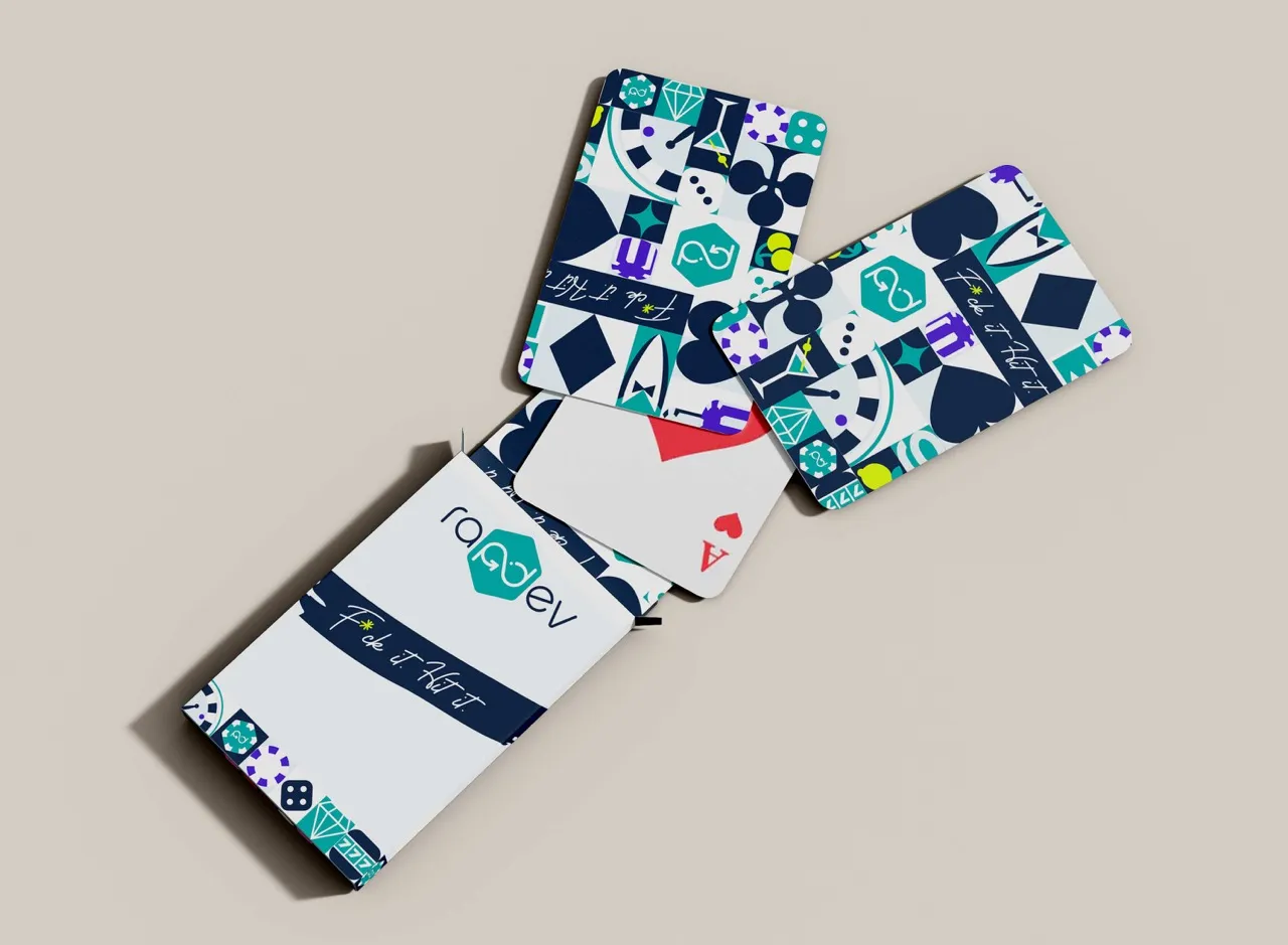 Colorful playing cards partially out of a branded box on a neutral background.