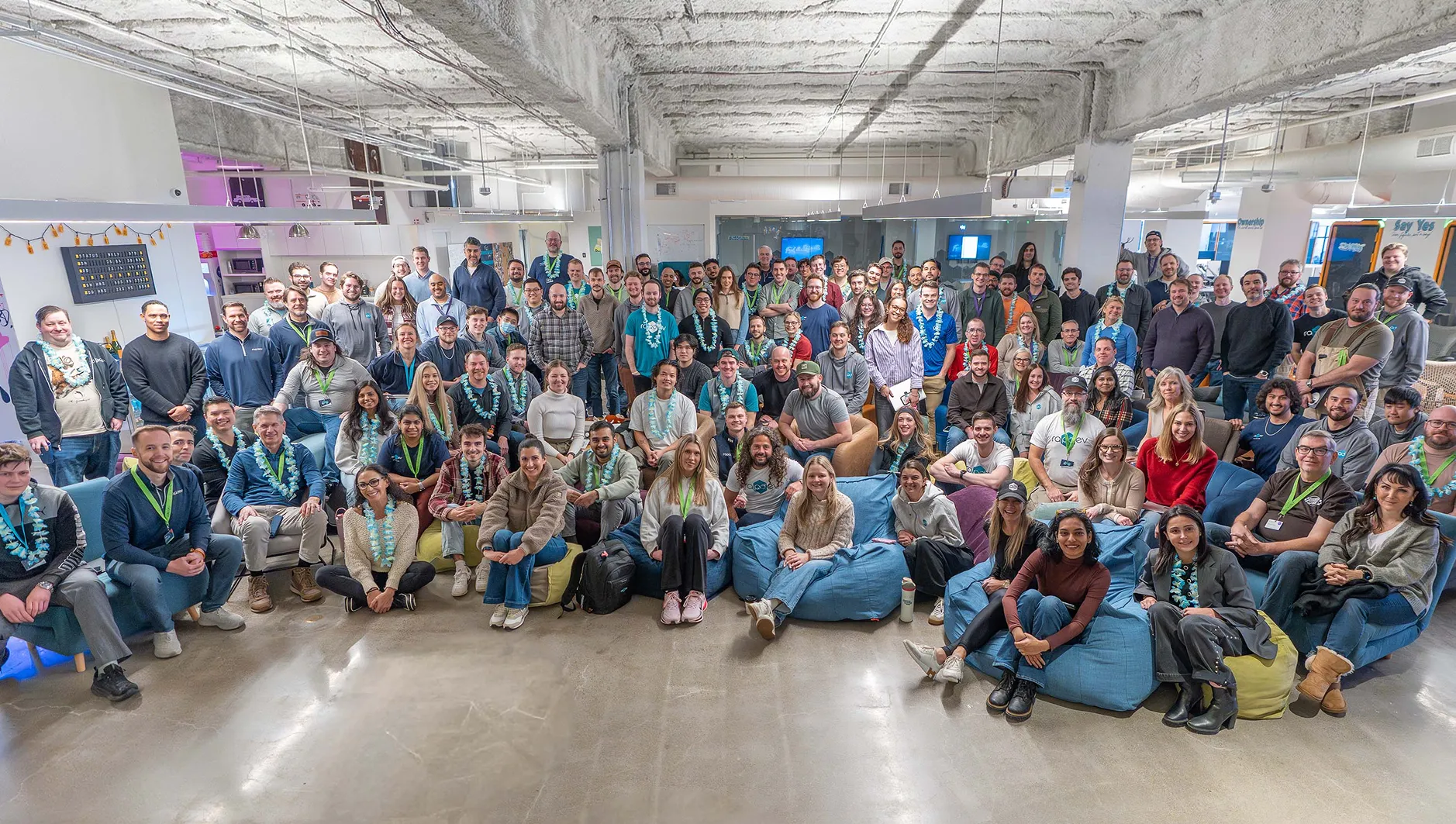 Group photo of a large team gathered in a modern workspace.