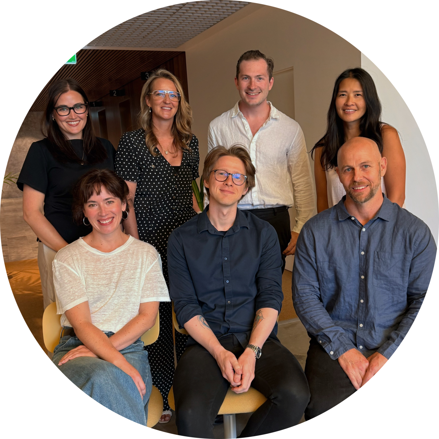 Five diverse professionals smiling and standing together in an office environment.